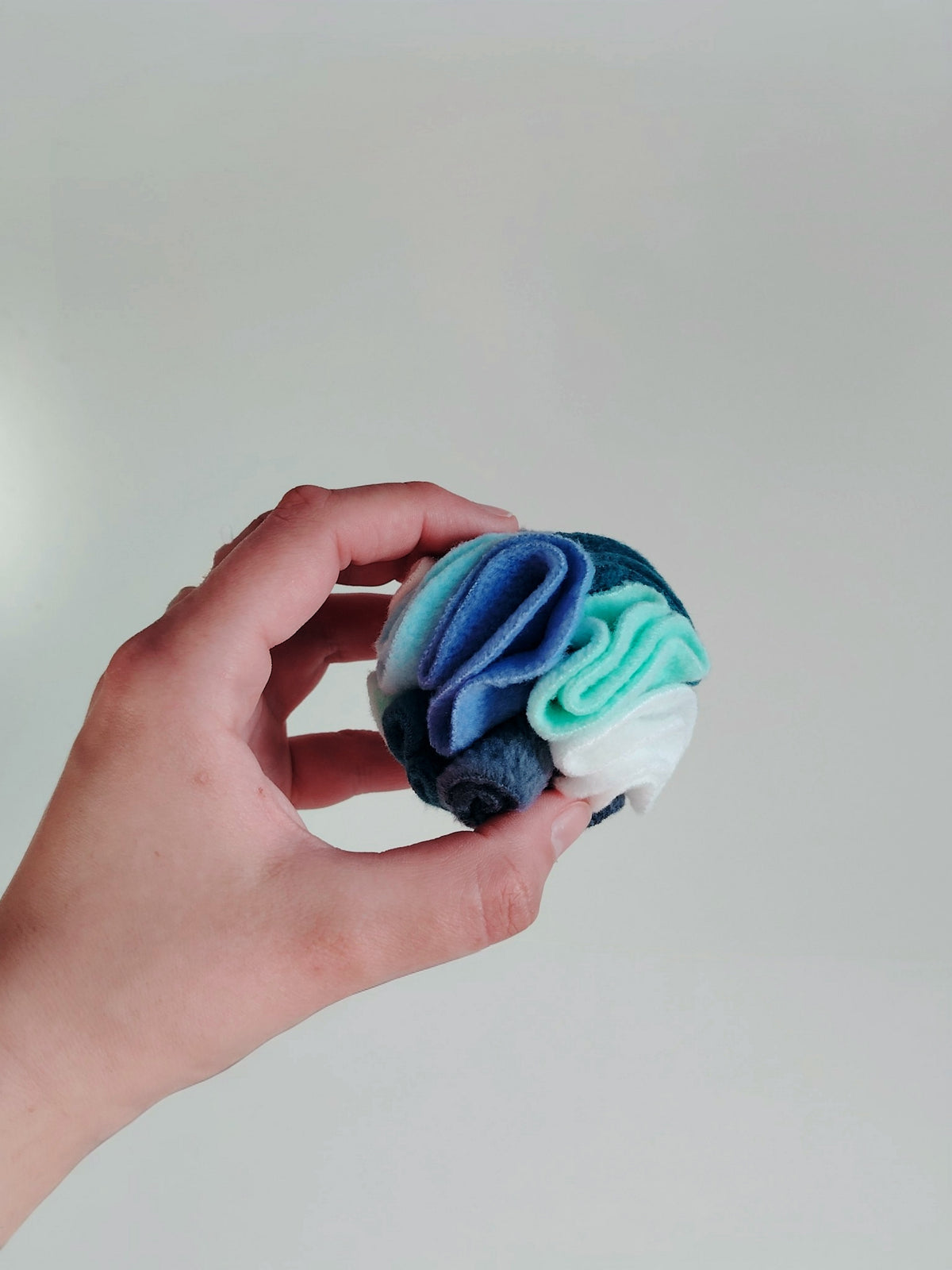 Hand holding pocket snuffle ball showing size for small dog enrichment toy.