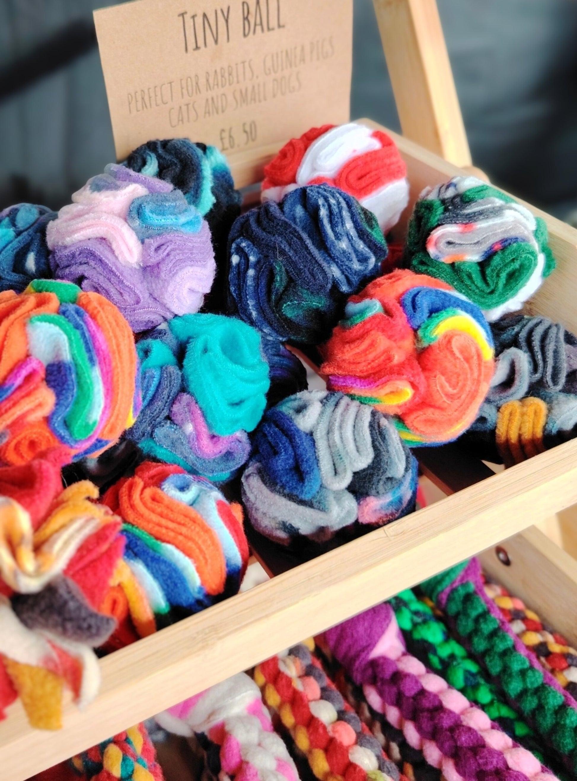 Colourful tiny snuffle ball for small animals displayed on a wooden stand.