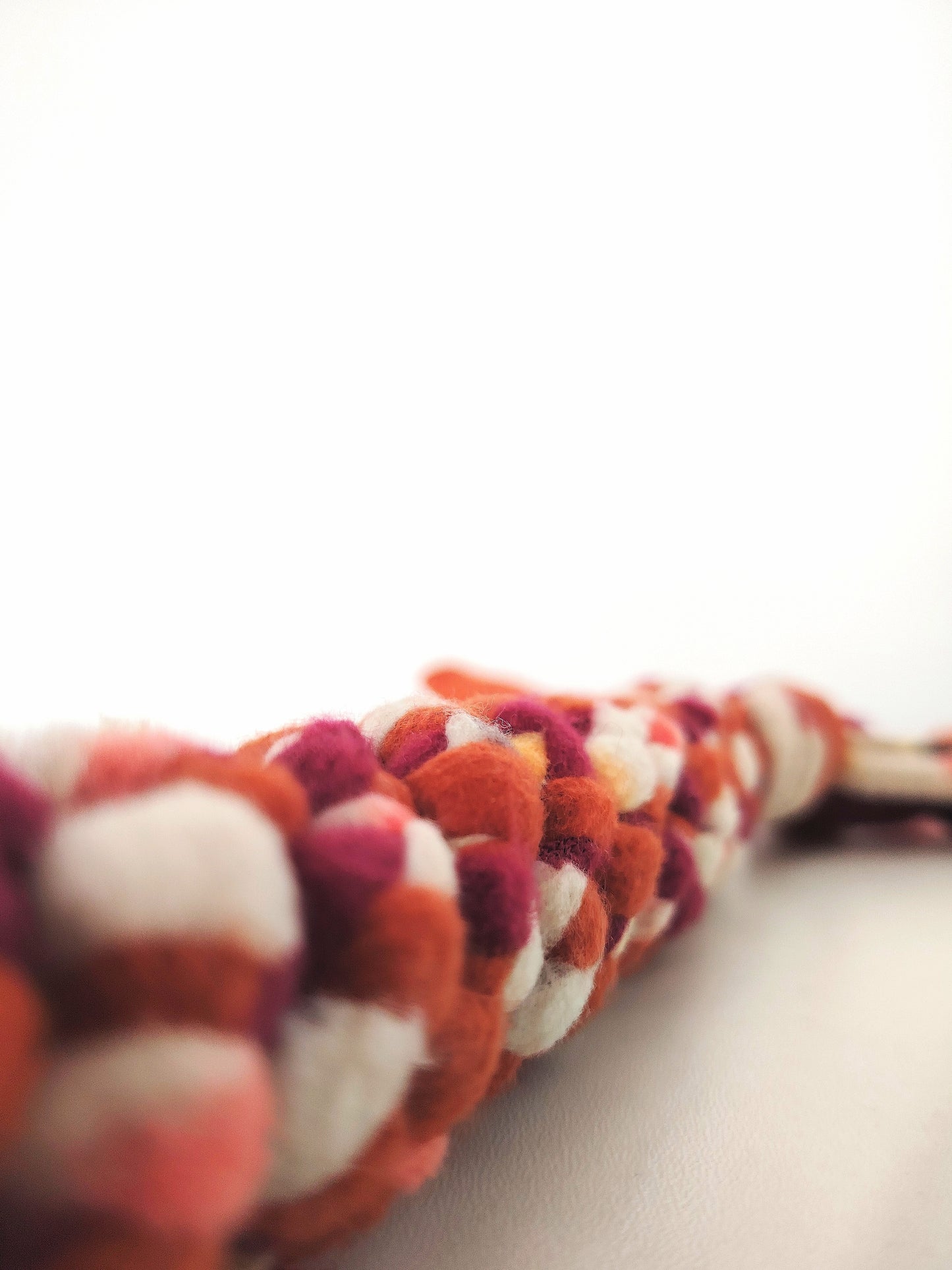 Close-up of the braided fleece texture of the Autumn handled dog tug toy in warm seasonal colours.