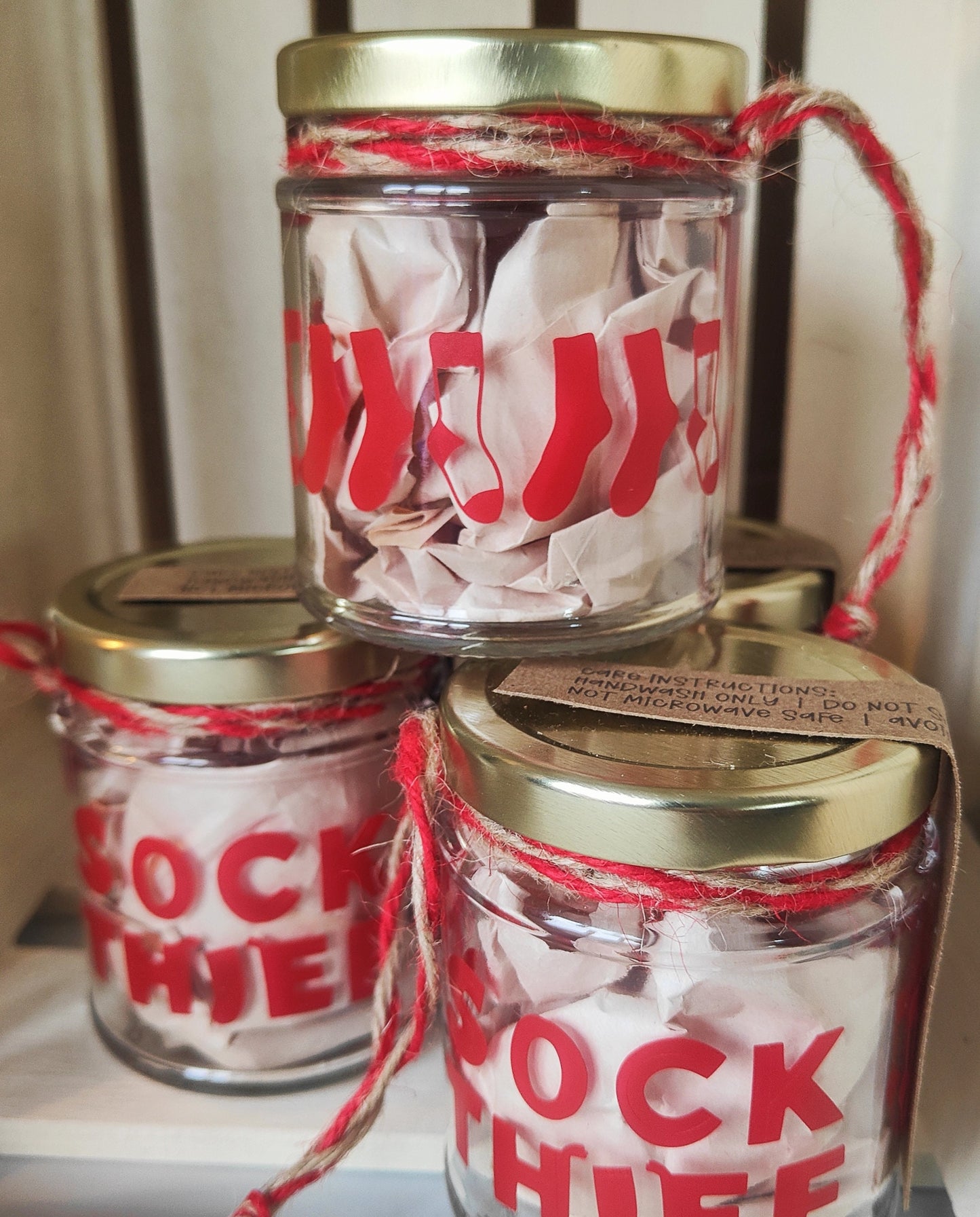 Three jars with gold lids and red text on a white surface