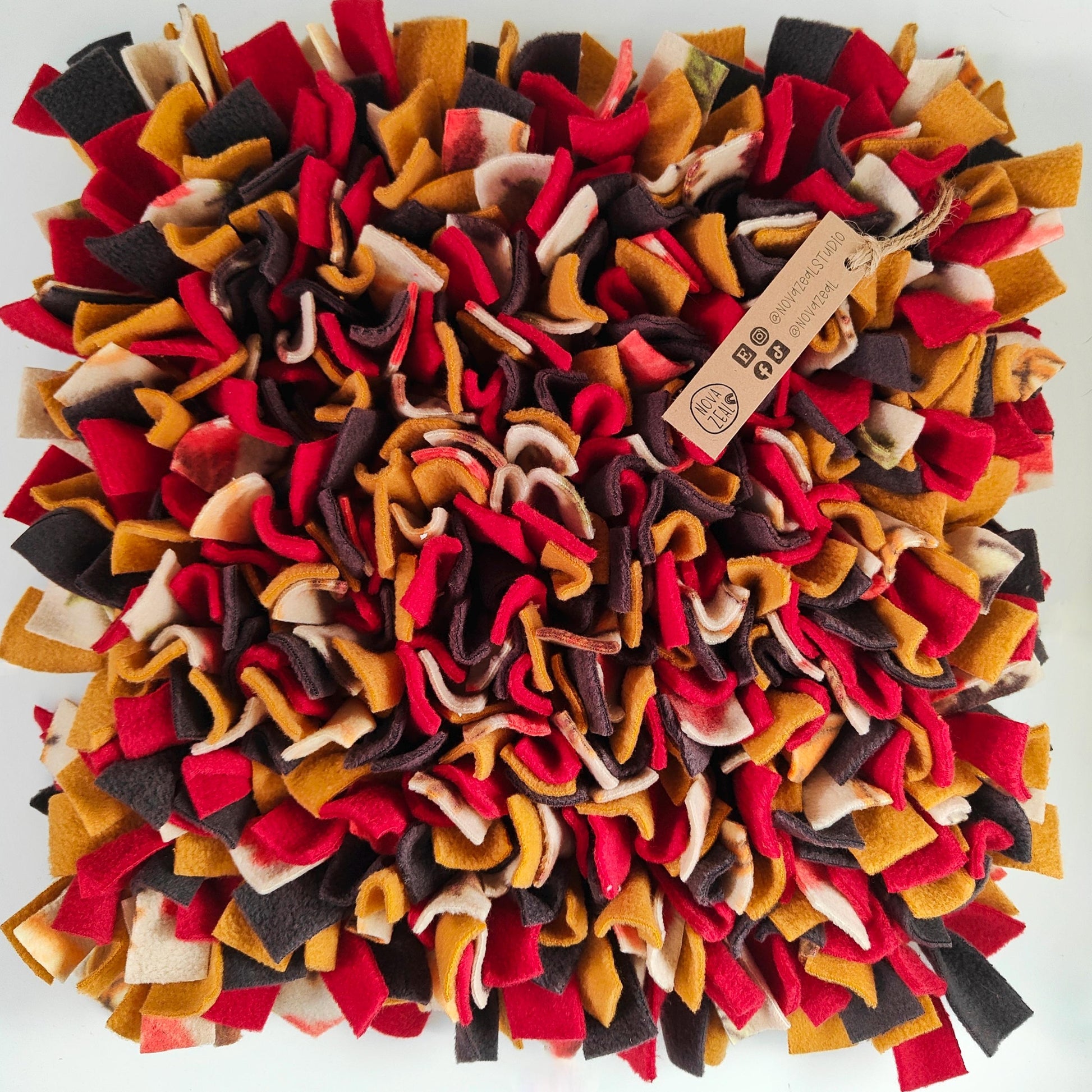 Rich Warm Autumn coloured fleece enrichment toy with a brand tag on a white background