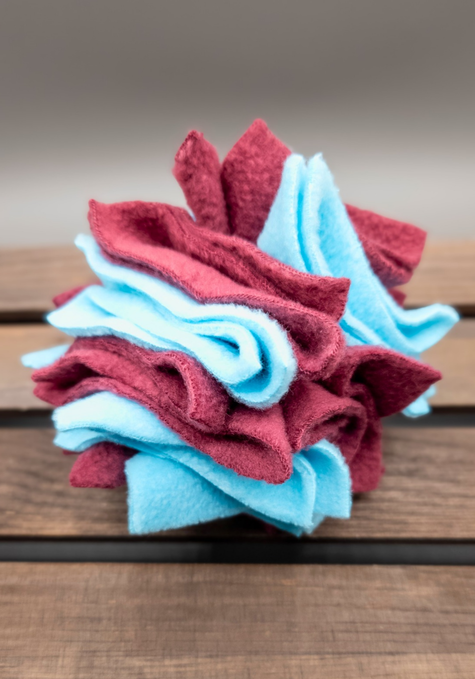 Calm blue and dark purple scruffle ball on a wooden surface