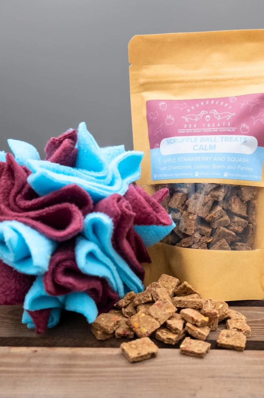 Dog scruffle ball and treats on a wooden surface with a grey background