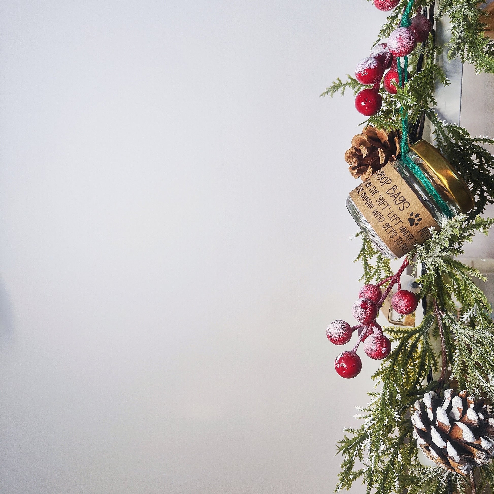 A simple Image with Christmas foliage and amongst it hangs the vibrant emerald green stocking filler decoration.