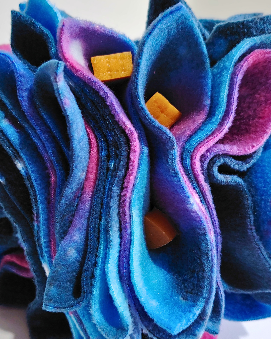 Close-up of blue and pink textured fabric with small treats inside.