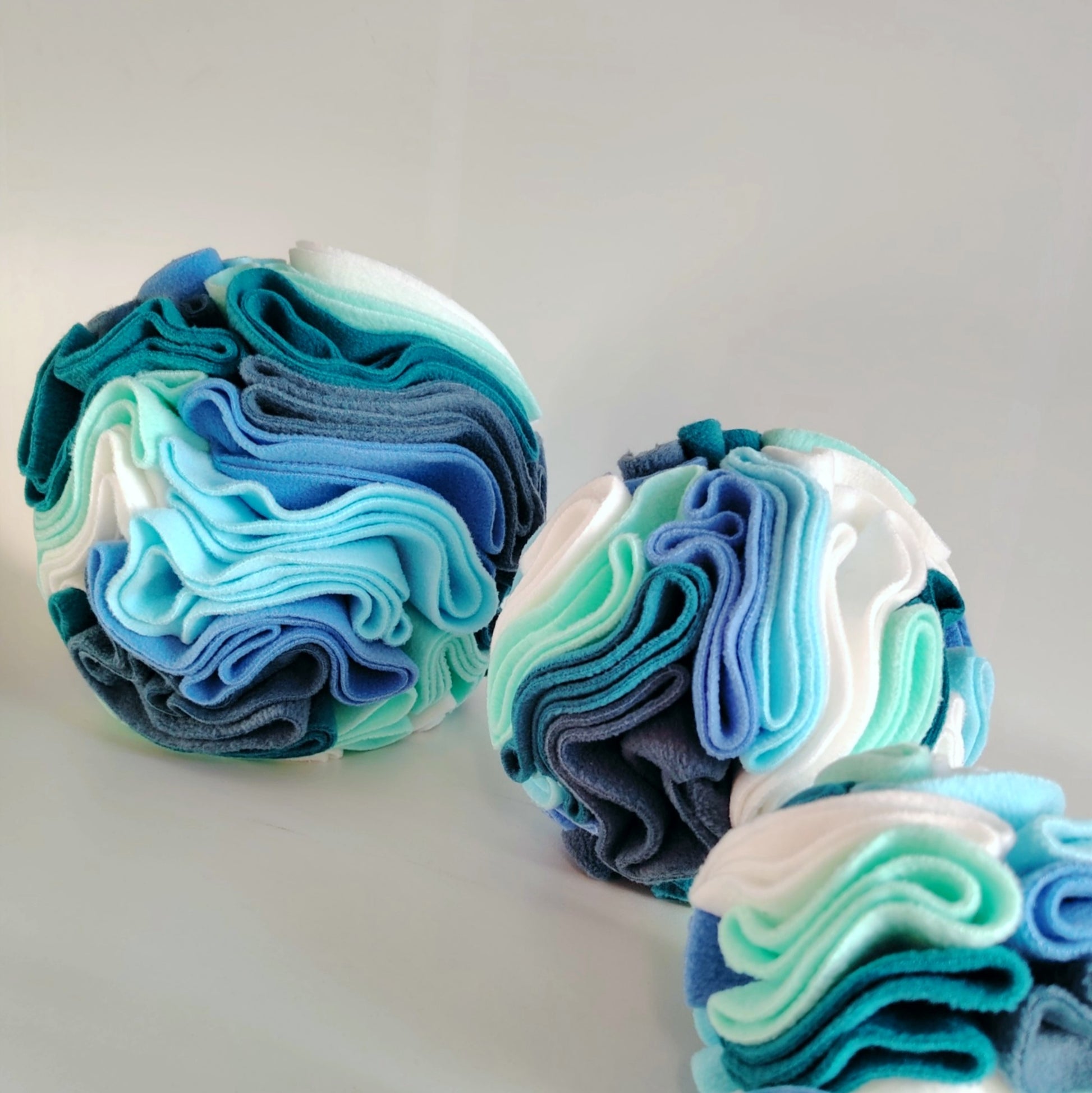 Group of cool tone snuffle balls in different sizes for dog enrichment.
