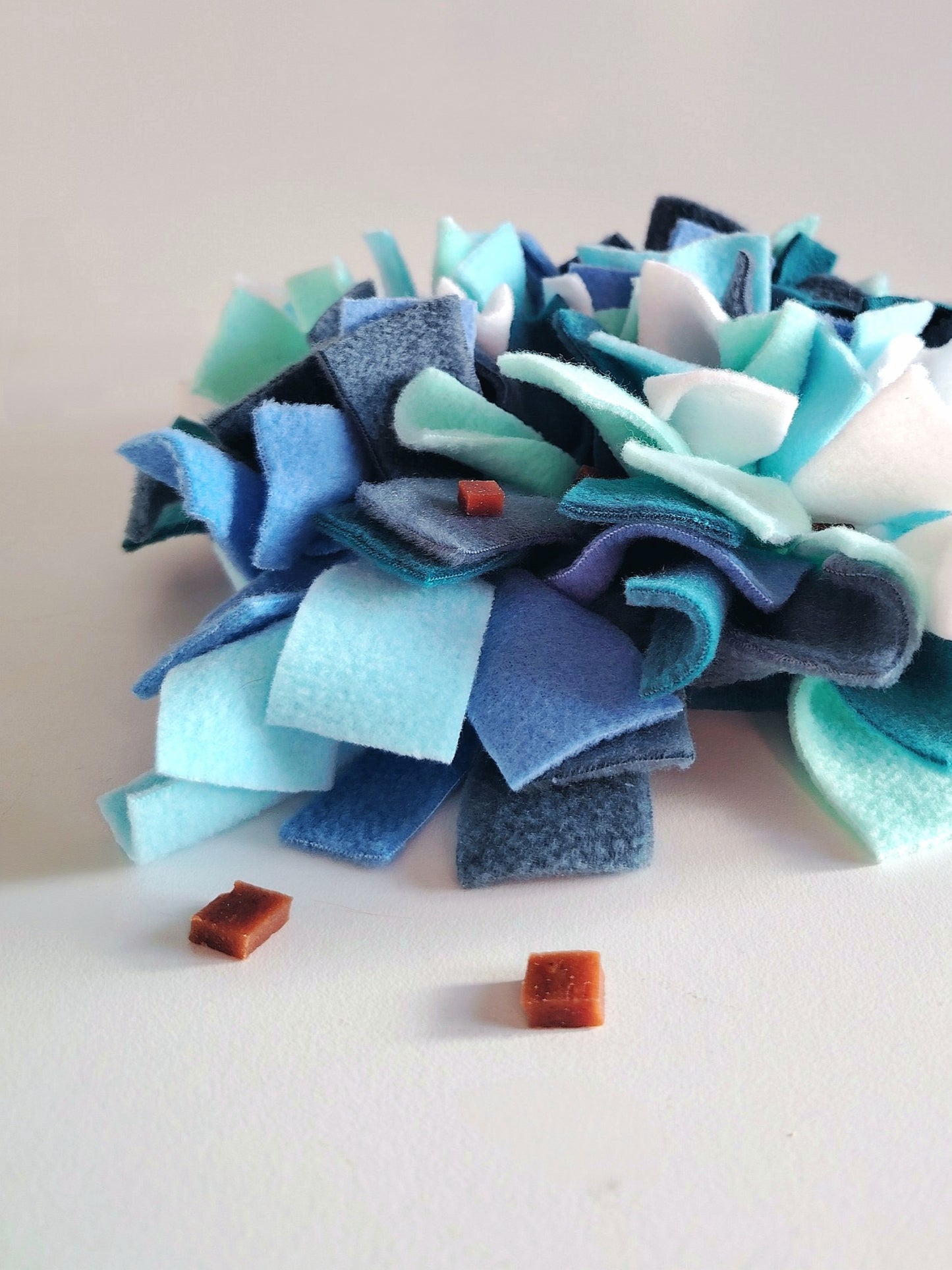 Dog treats hidden in cool-toned snuffle mat for foraging play.