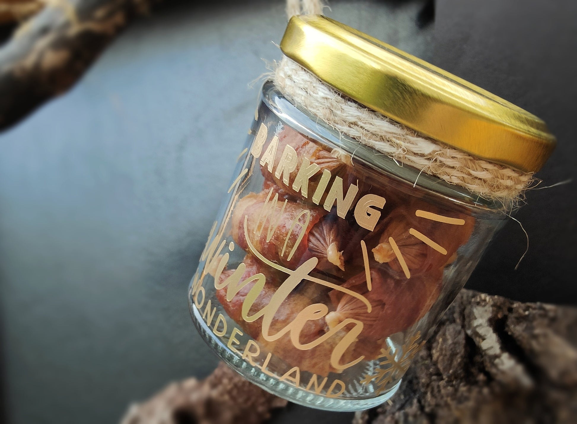 Jar of treats with a gold lid and jute for hanging on a dark surface