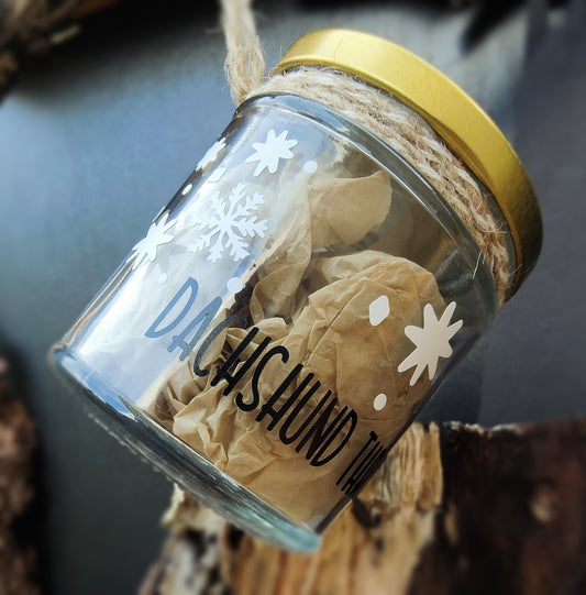 Glass jar with gold lid containing crumpled tissue paper and decorative elements on a dark background