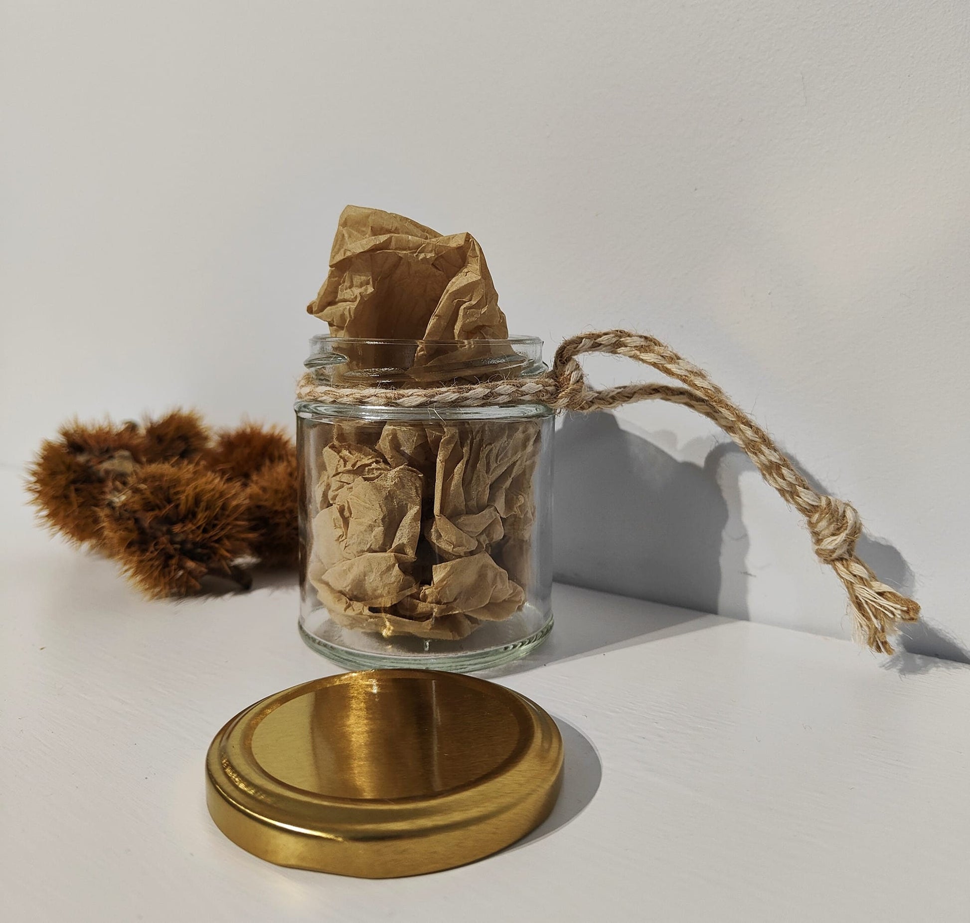 The back of the glass jar with tissue paper inside and a gold lid on a white background