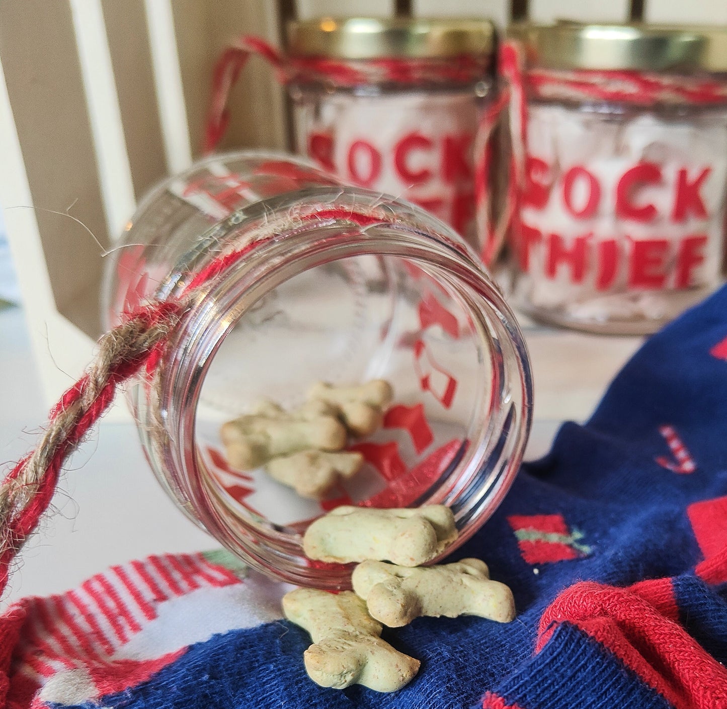 Glass jar with dog treats scattered on top of festive socks with more jars in the background
