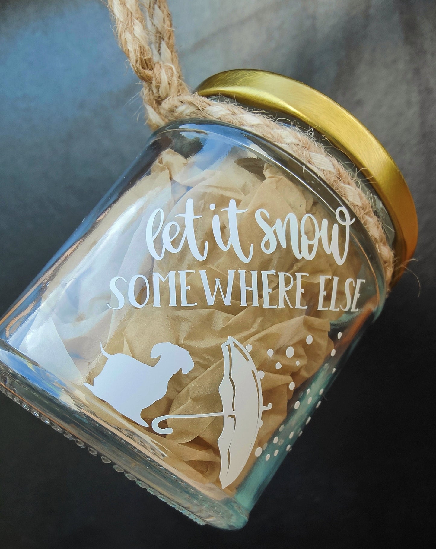 Glass ornament with gold lid featuring winter-themed design and text.