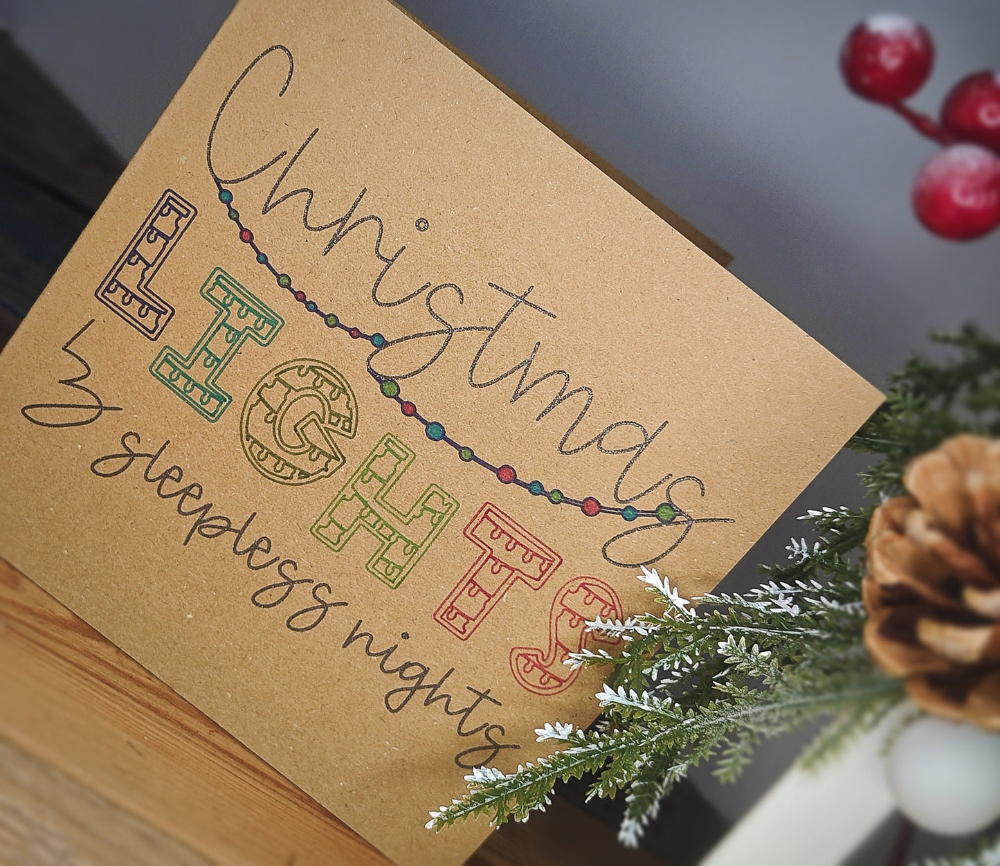 Kraft paper card with 'Christmas Lights' and 'sleepless nights' text, surrounded by Christmas decorations.