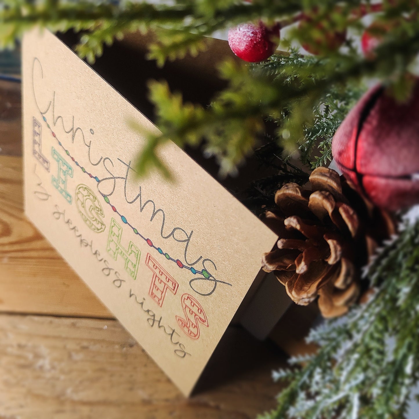 Looking down at a Christmas card with decorative elements on a wooden surface