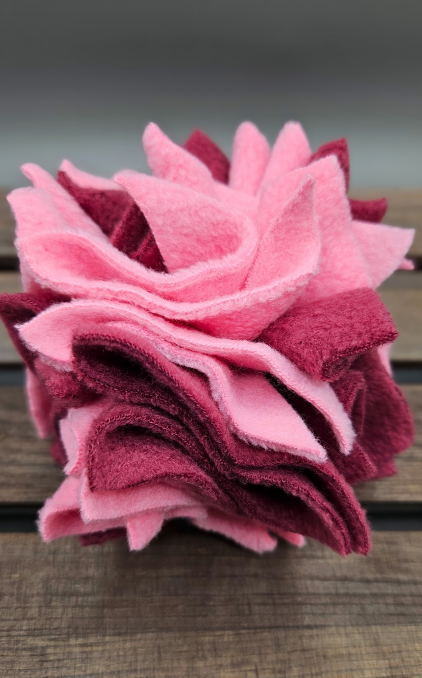 Joint support pink and dark purple fleece enrichment aid on a wooden surface