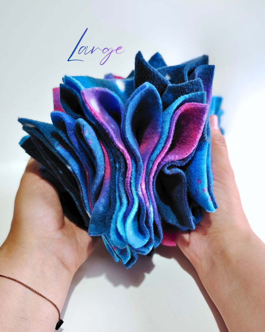 Blue and pink fleece enrichment toy held in hands with 'Large' text above on a white background