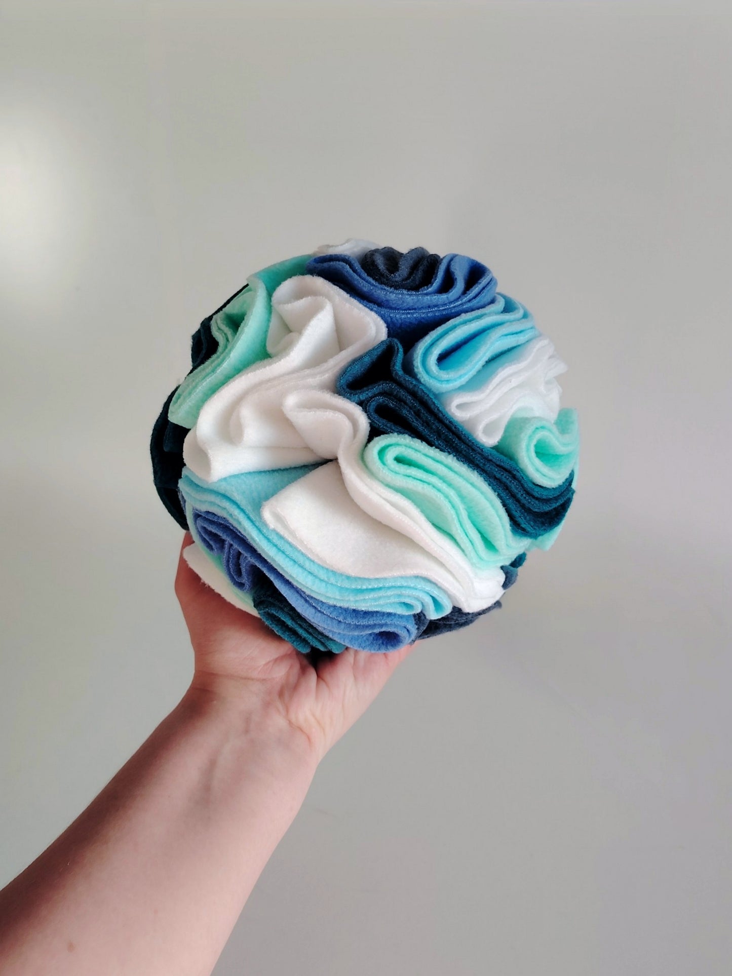 Medium snuffle ball held in hand showing scale and fleece layers