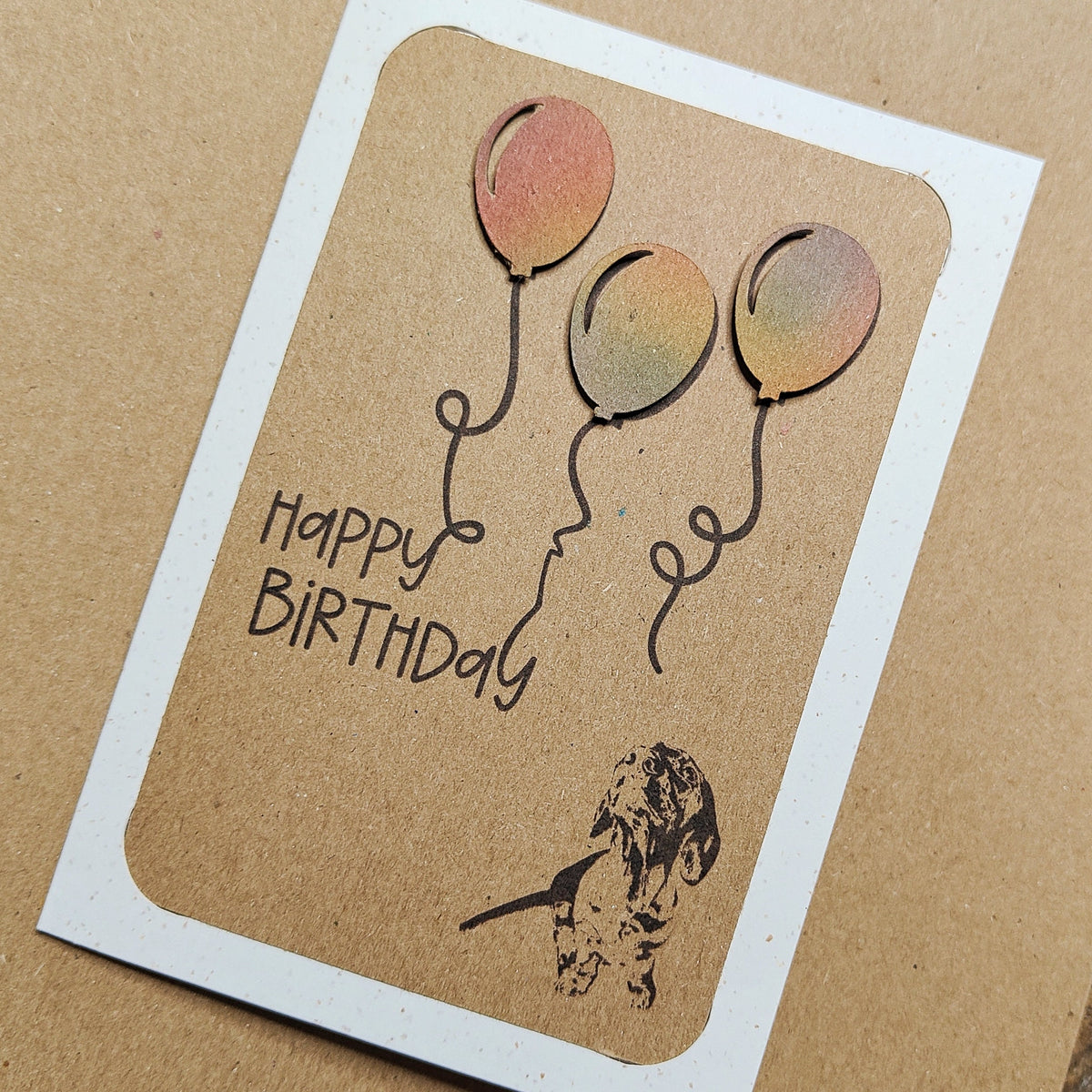 Close-up of a Miniature Dachshund birthday card with colourful raised balloons and Happy Birthday text.
