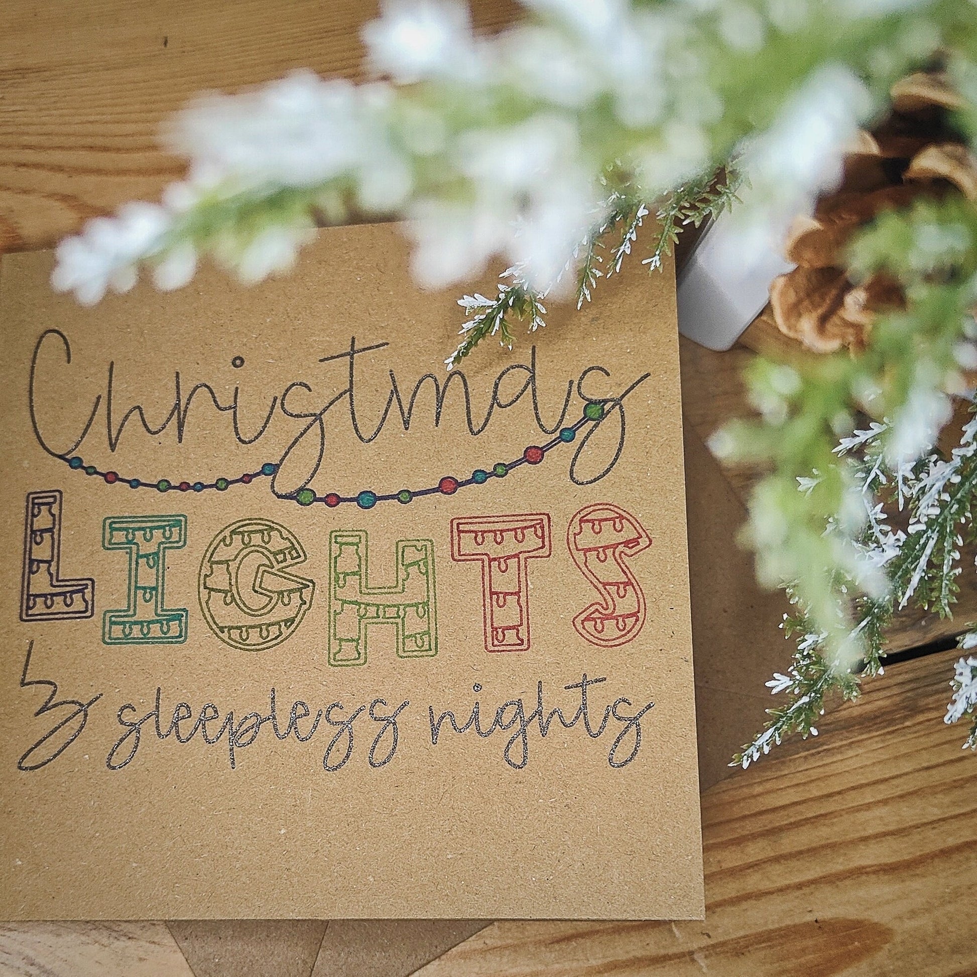 Kraft Card with 'Christmas Lights & Sleepless Nights' text on a wooden surface with festive decorative elements.