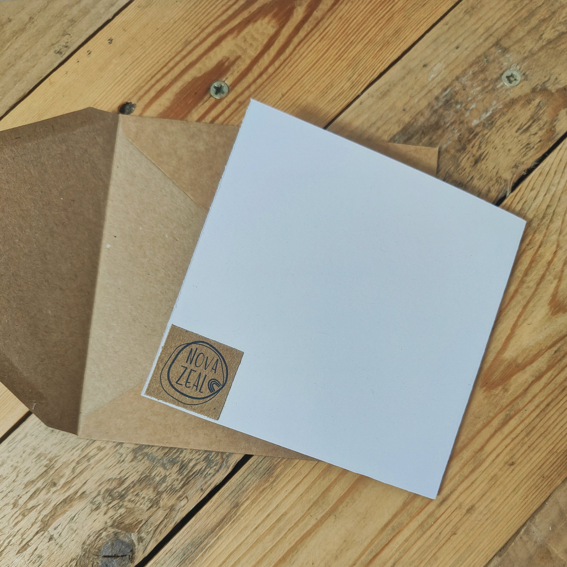 White card with a brown envelope on a wooden surface, featuring a 'Nova Zeal' logo.