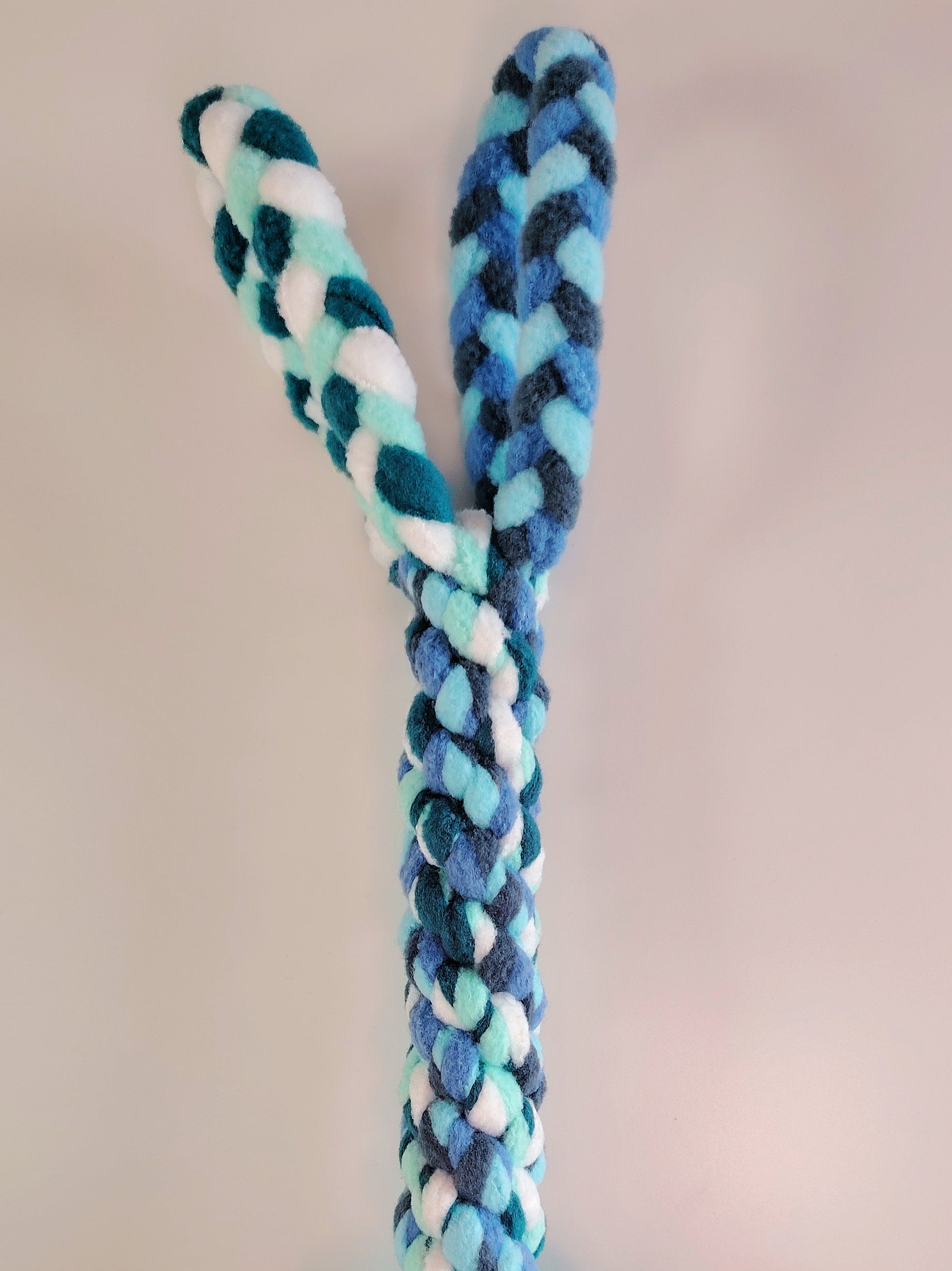 Braided fleece dog tug toy showing strong woven design in cool blue and green tones.