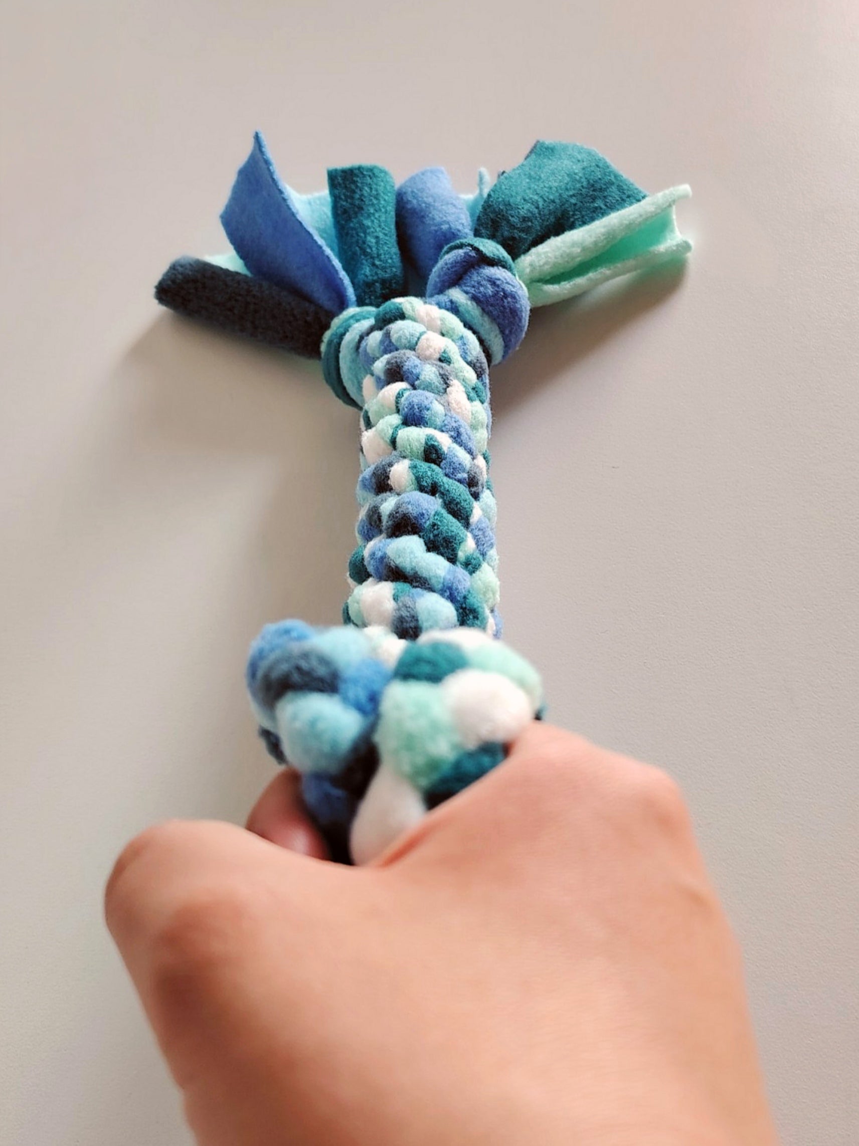 Hand holding cool colour fleece dog tug toy showing interactiveplay use.