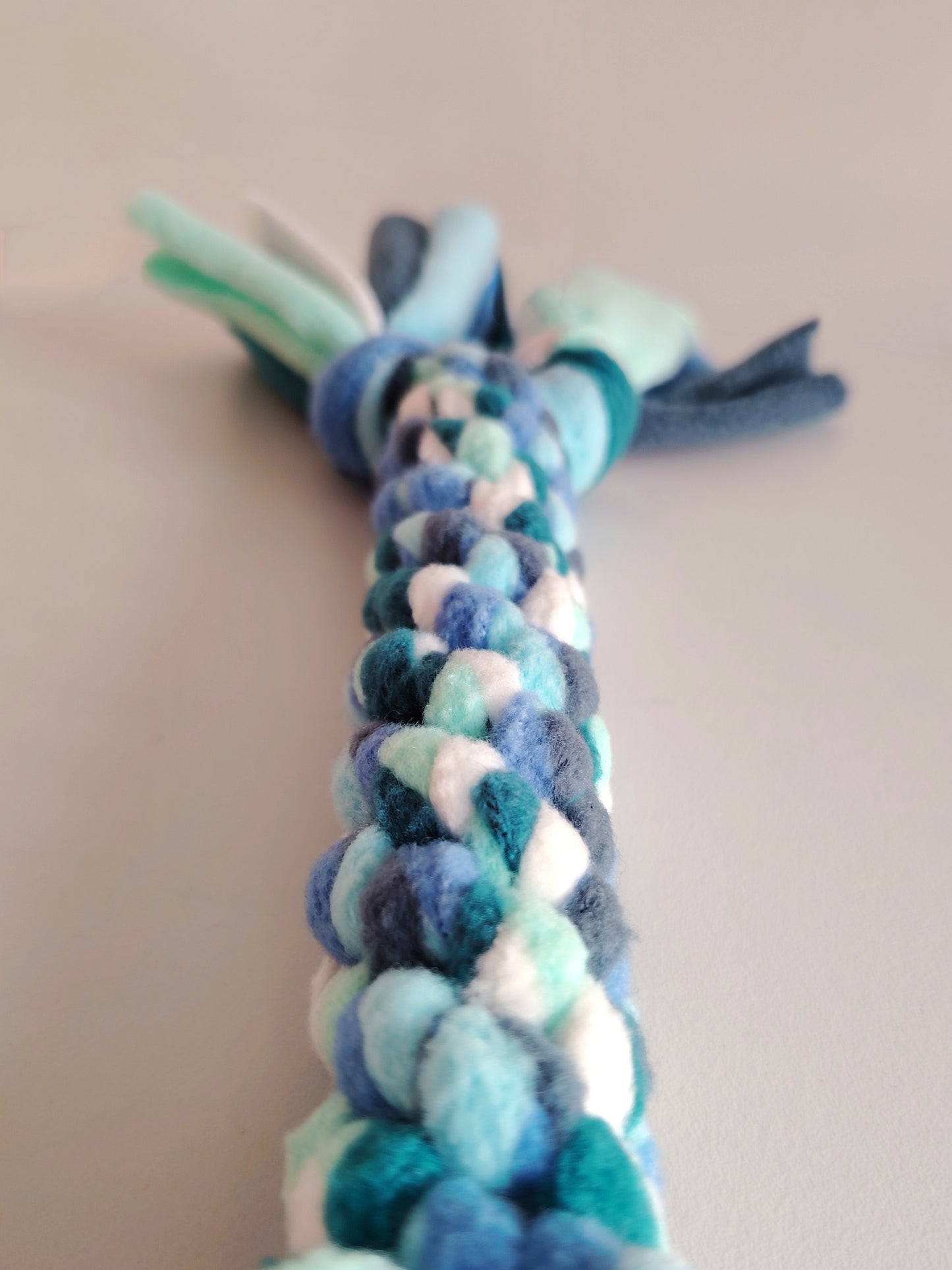 Close-up of braided fleece texture on cool colour dog tug toy.
