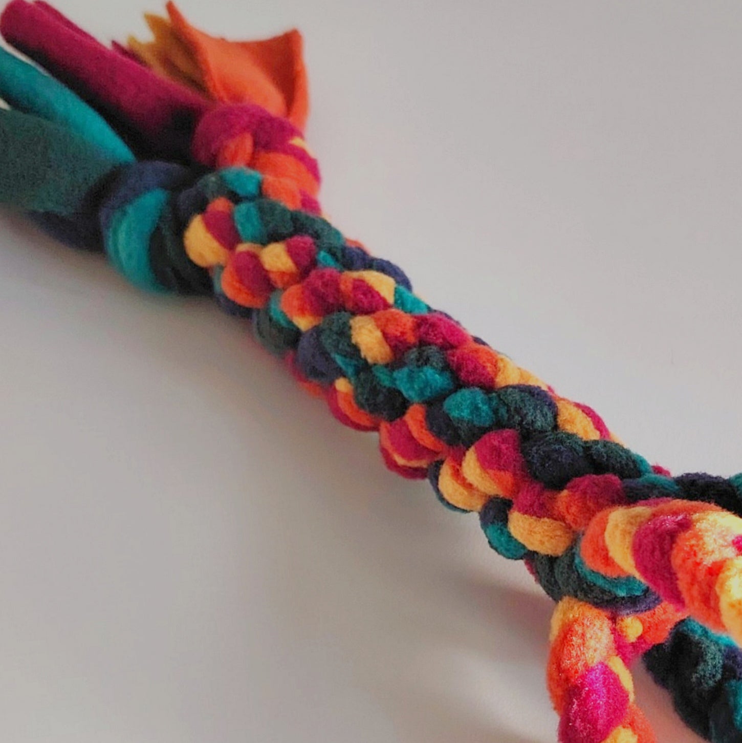 Close-up of braided fleece texture on warm colour dog tug toy.