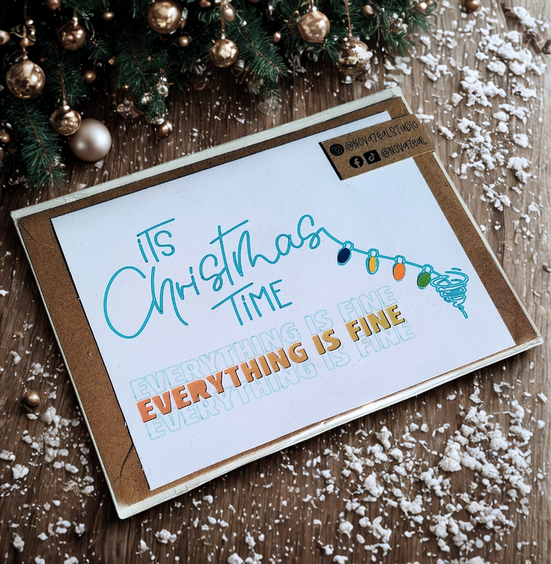 Orange variation of the 'It's Christmas TIME... EVERYTHING IS FINE' Dog-themed Christmas Card. Winter Decoration behind the greetings card.