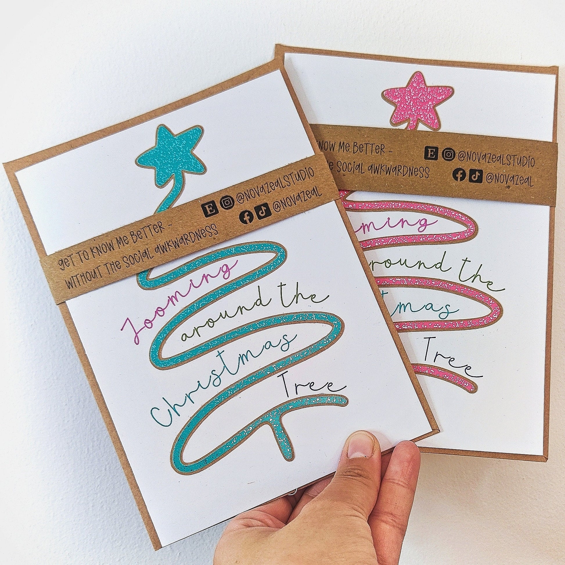 Showing two colour variations of the dog-themed Christmas card with decorative elements, text on a white background and a brown envelope.