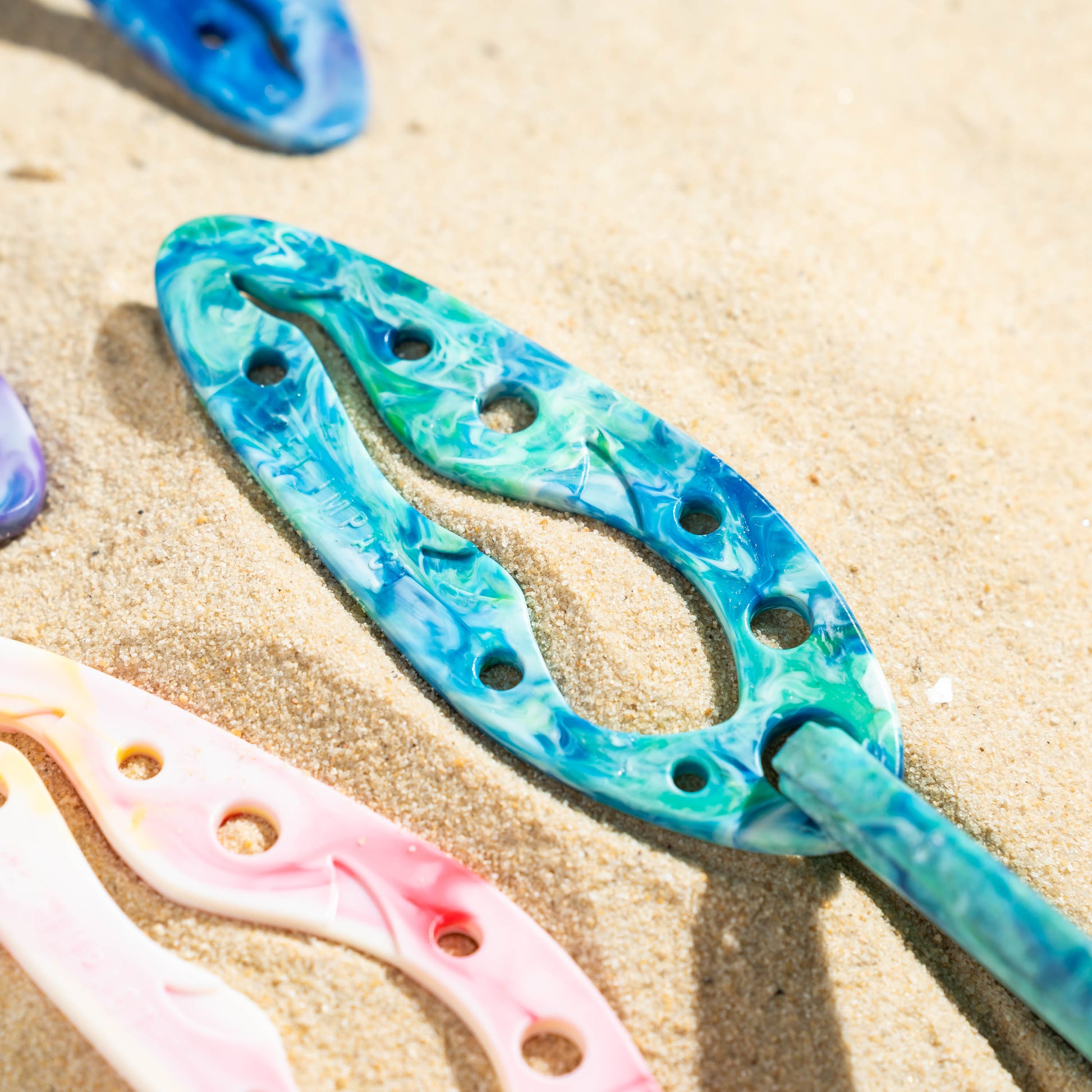 Close-up of the Turquoise PooPal recycled dog poo bag holder with matching carabiner, designed to carry tied poo bags hands-free during walks.