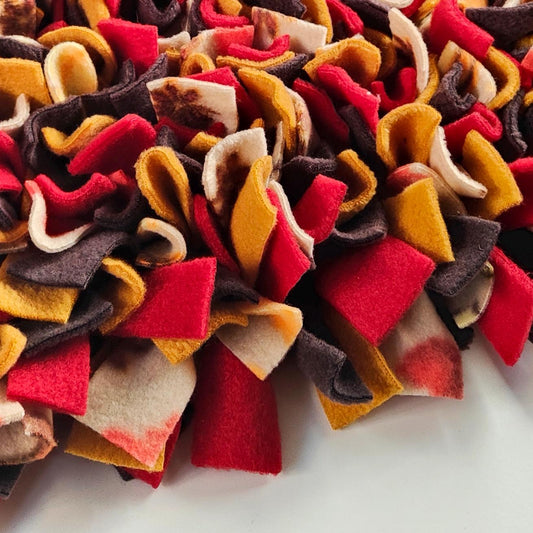 Close-up of a colourful fleece snuffle mat with autumnal tones on a white background