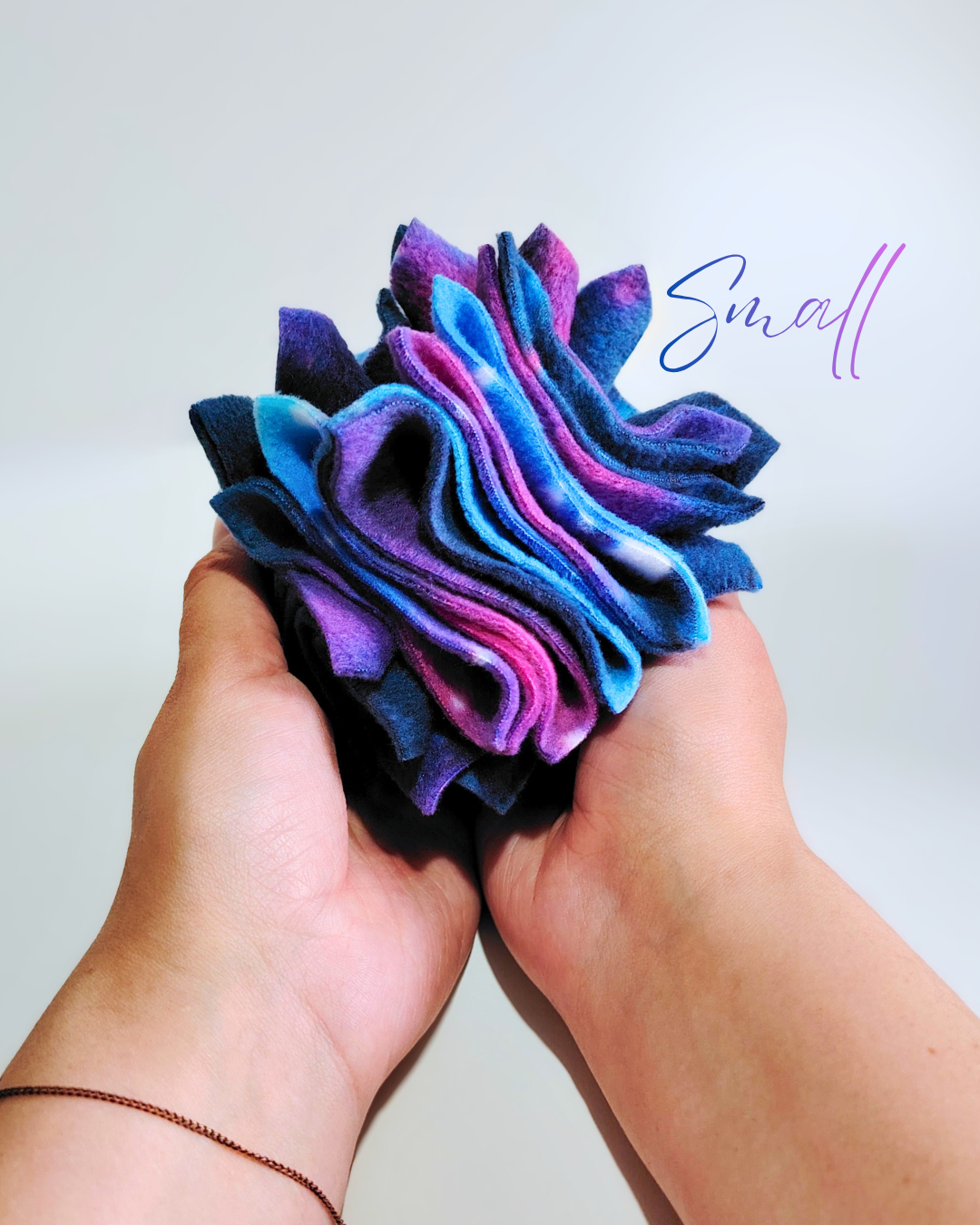 Galaxy fleece fabric scruffle ball held between two hands with 'Small' text overlay on a light background