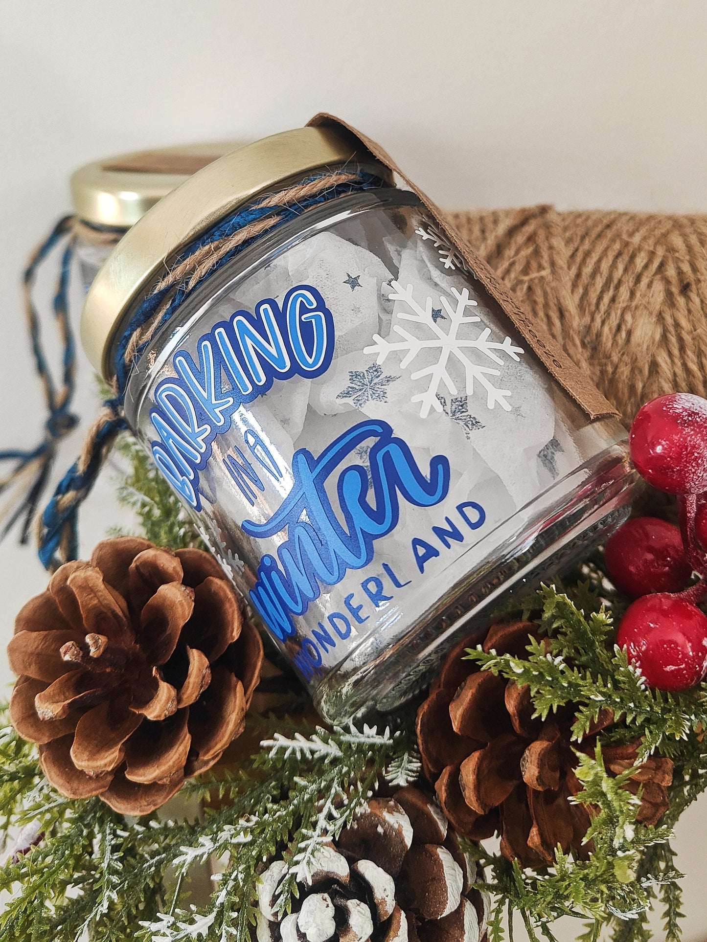 Jar with 'Barking in a winter wonderland' text surrounded by snowflakes. Christmas decorations behind the jar.