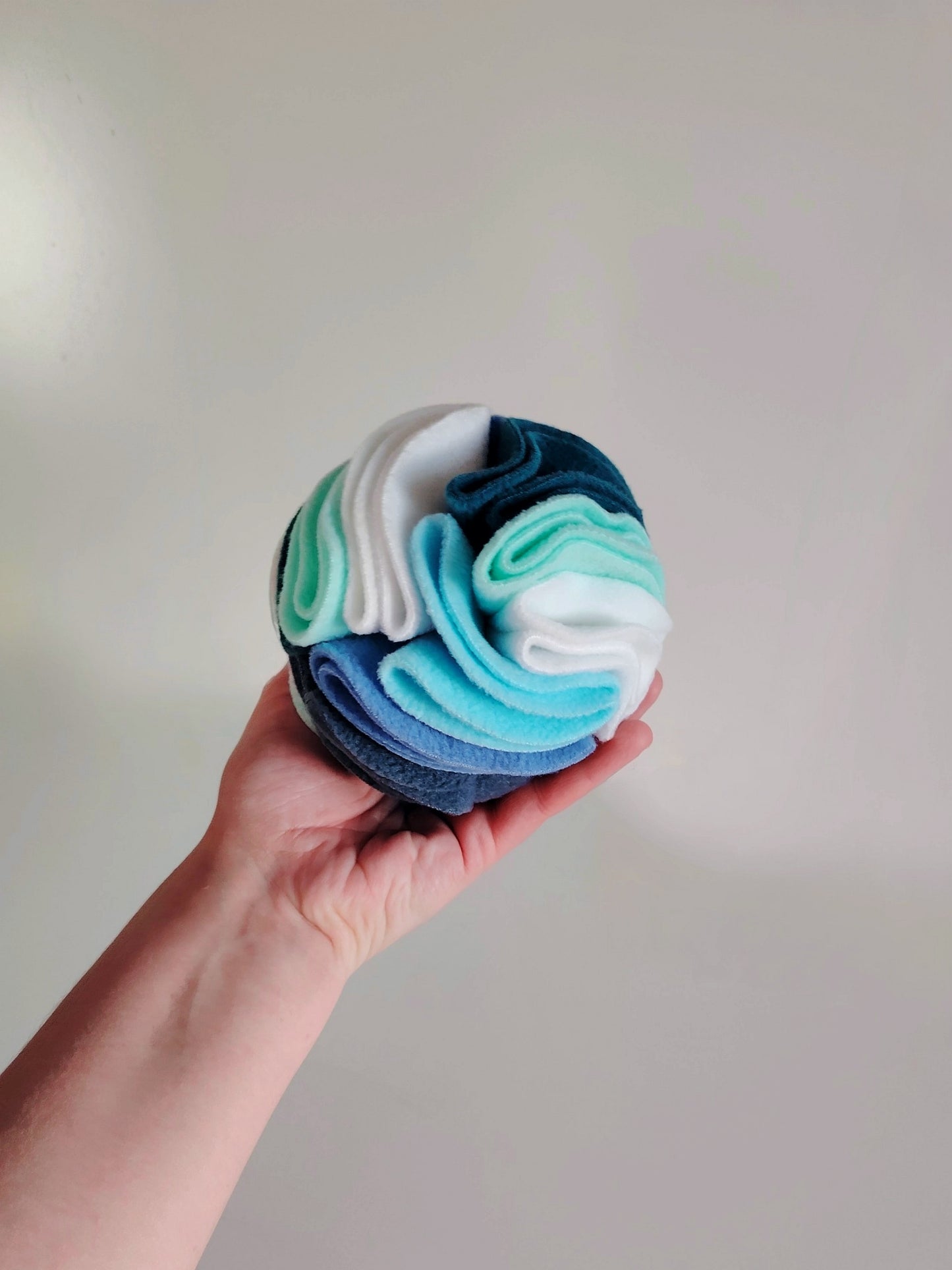 Small snuffle ball held in hand for size reference and enrichment use.