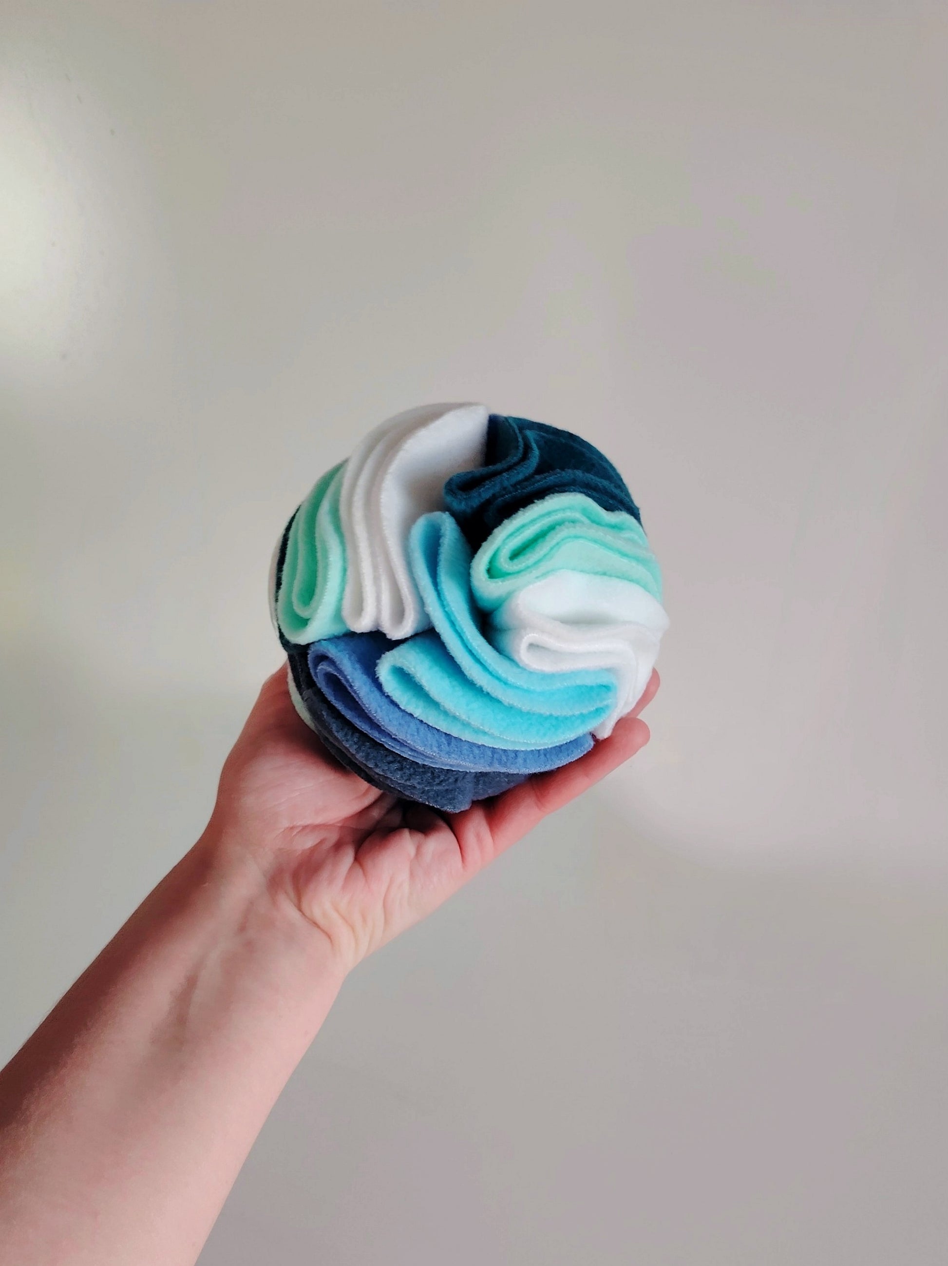Small snuffle ball held in hand for size reference and enrichment use.