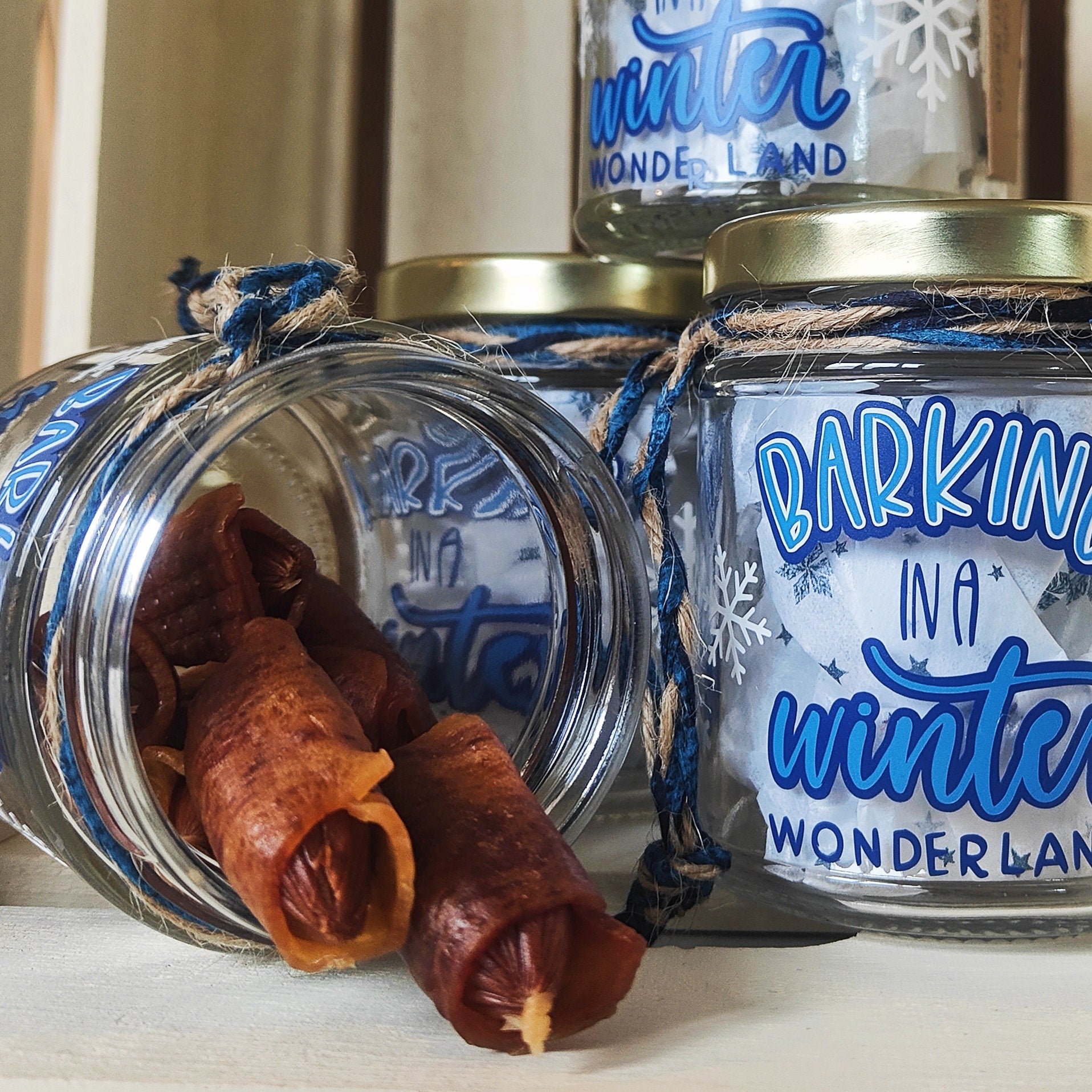Glass jars with dog treats and 'Barking in a Winter Wonderland' text on a light background