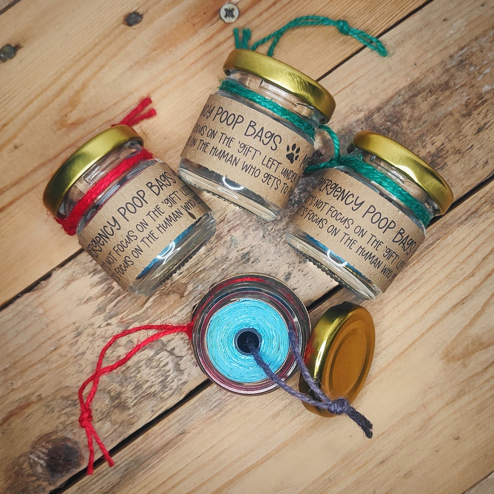 Three 'Emergency Poop Bag' Decorations showing the text on brown paper. One upright showing the contents of the blue poop bag roll.