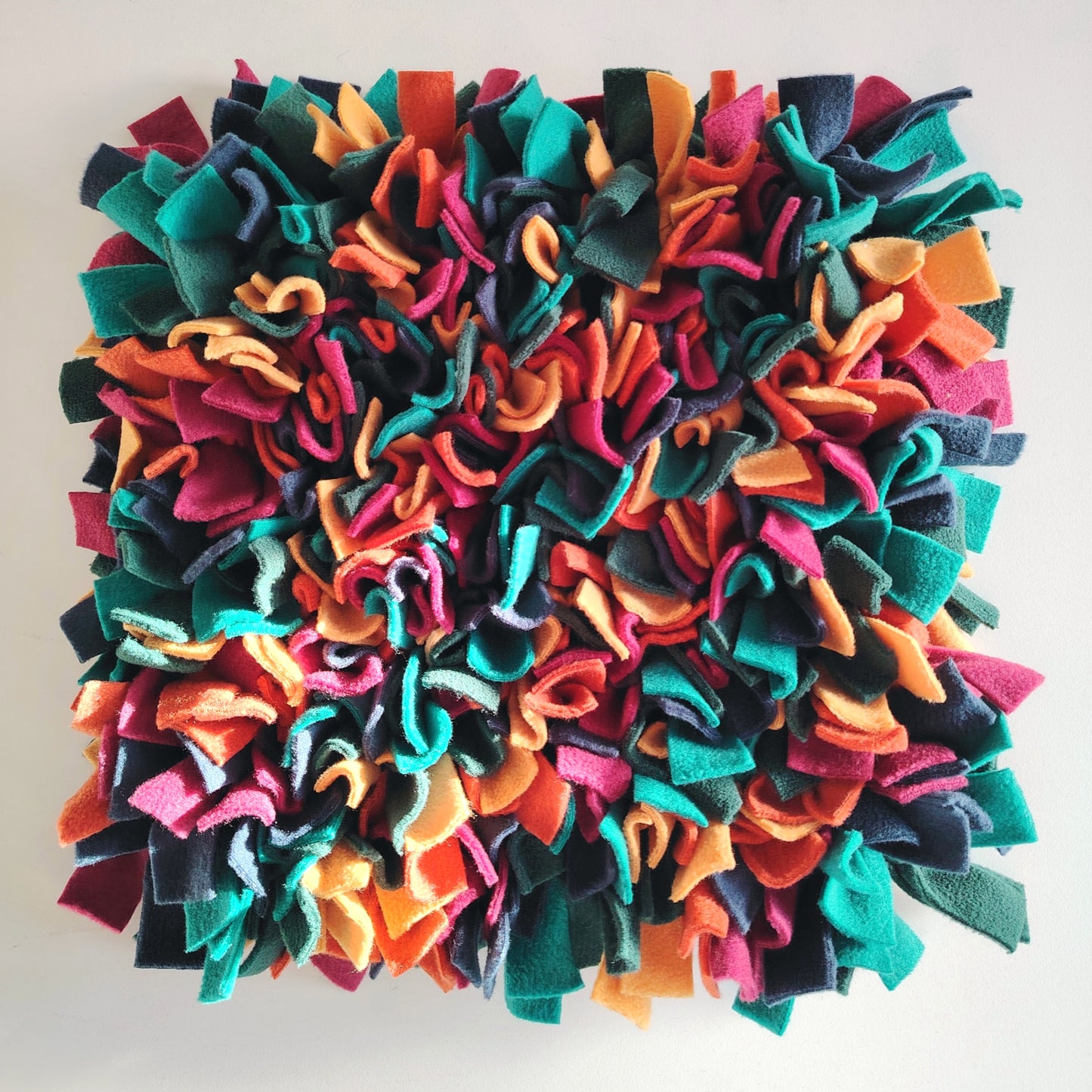 Top view of warm-toned snuffle mat with orange, green and deep colours of fleece.