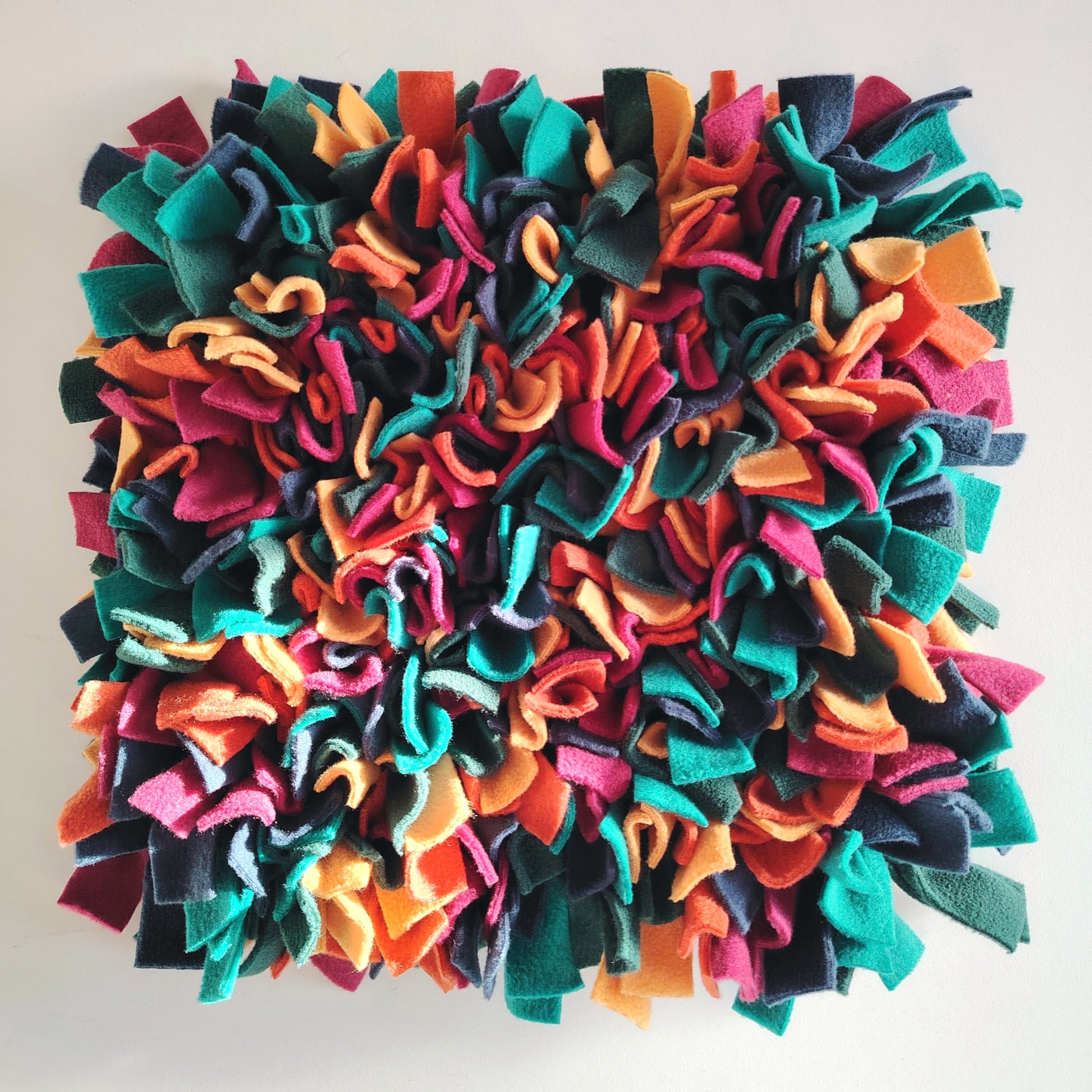 Top view of warm-toned snuffle mat with orange, green and deep colours of fleece.