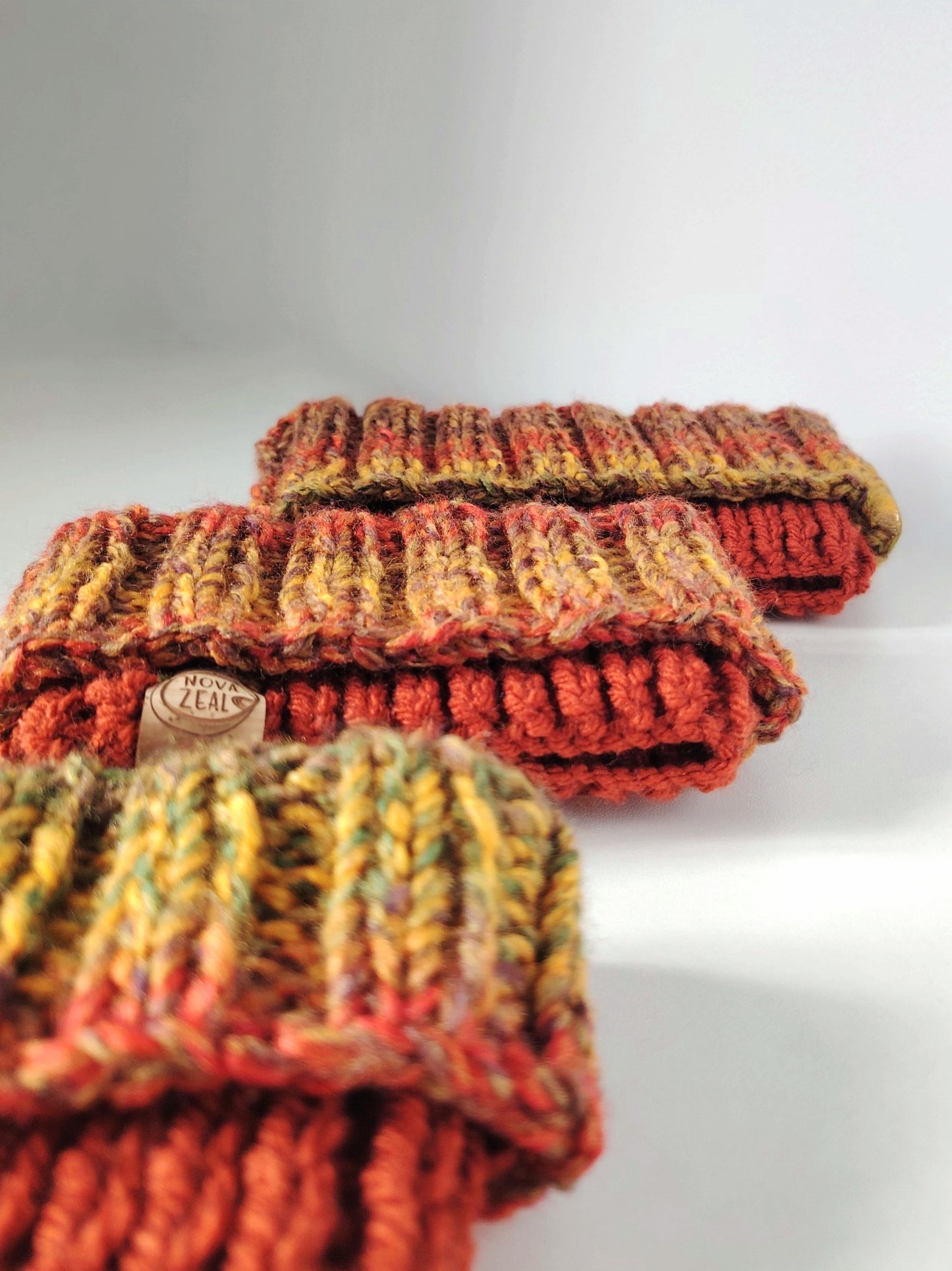 Close-up of Autumn hand-knitted dog snoods showing the textured knit and warm seasonal colours.