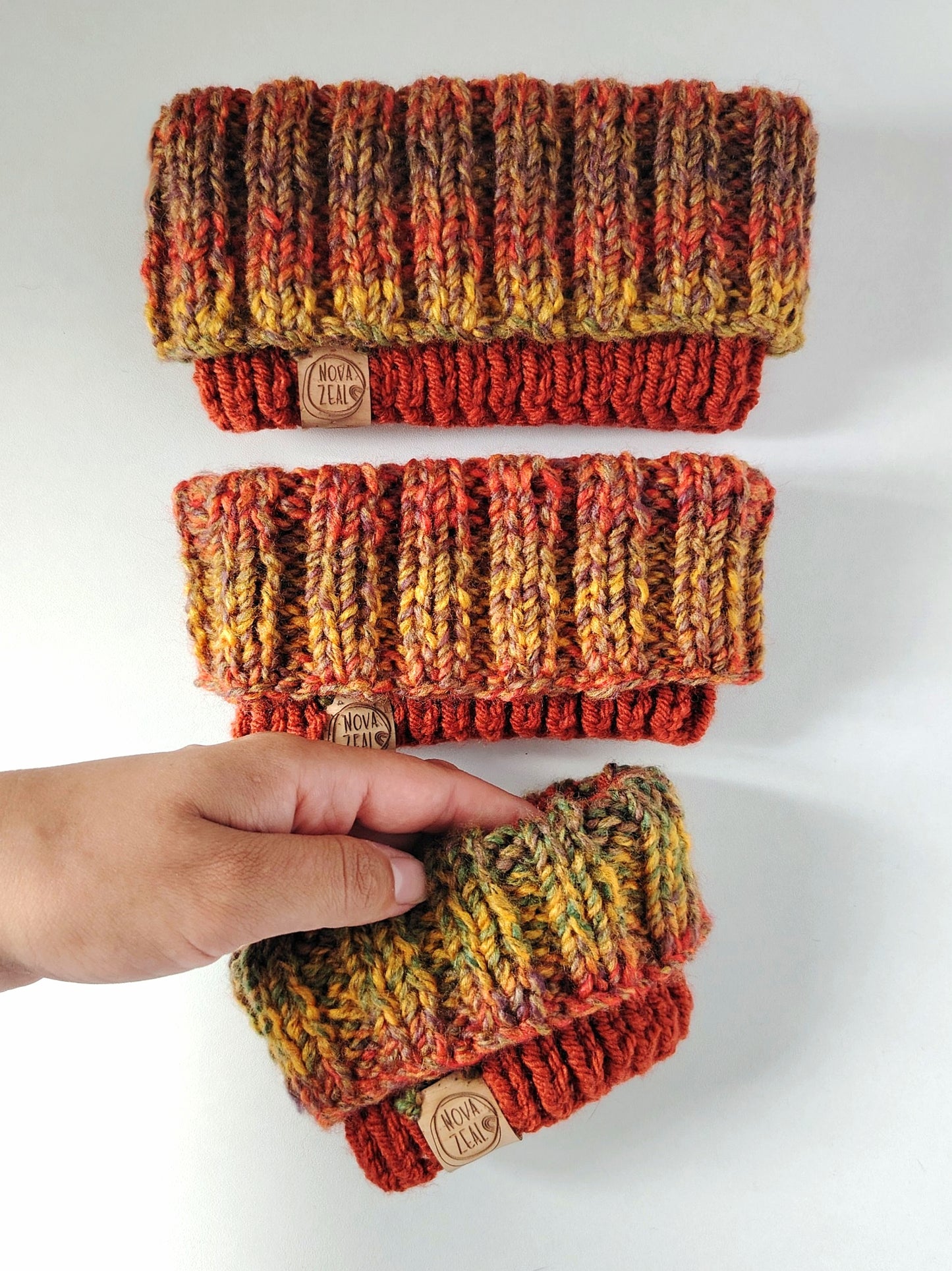 Autumn hand-knitted dog snoods in three sizes, featuring warm rust, mustard, moss green and brown tones.