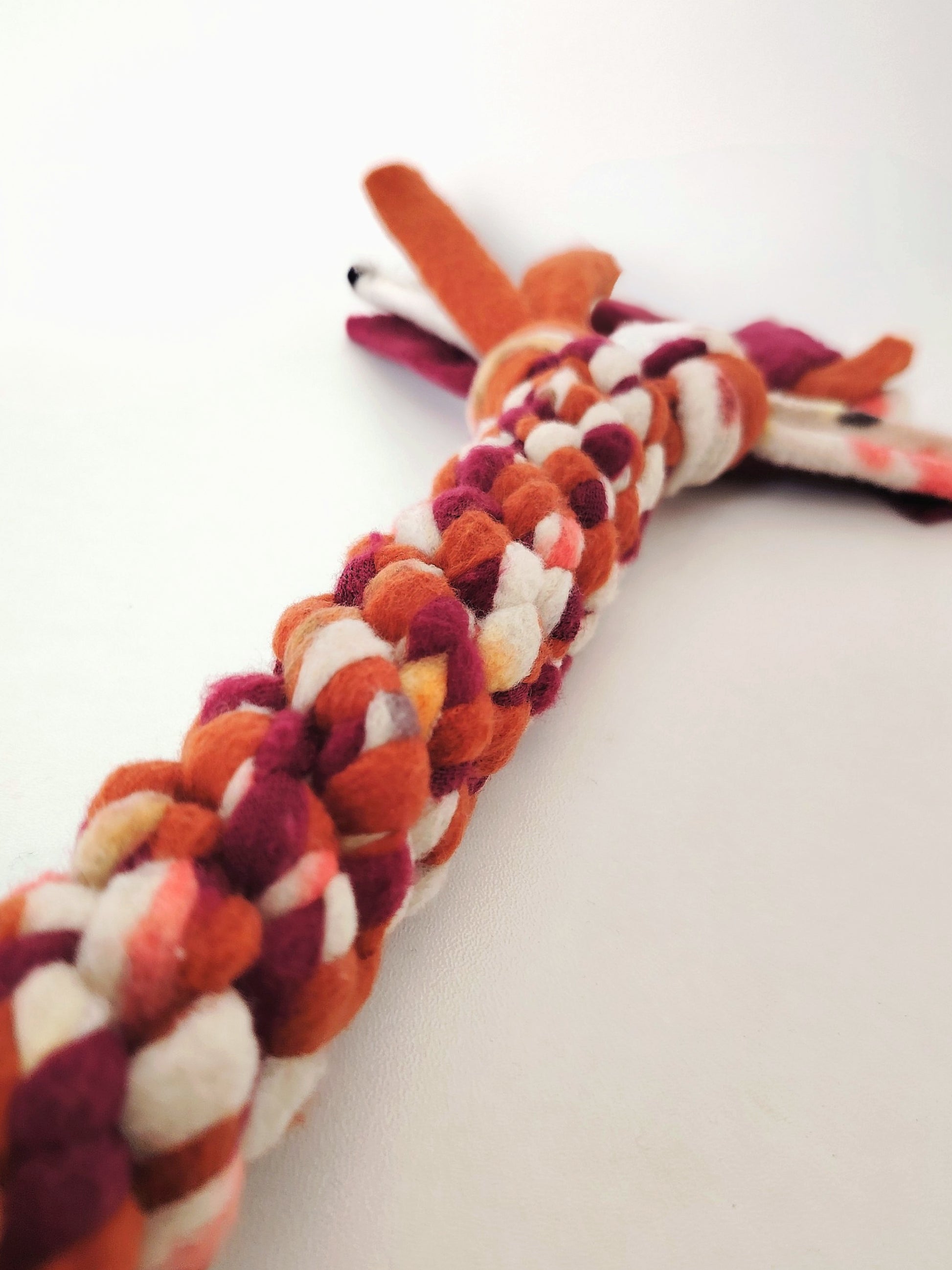 Close-up of the braided fleece on the Autumn handled dog tug toy in warm seasonal colours.