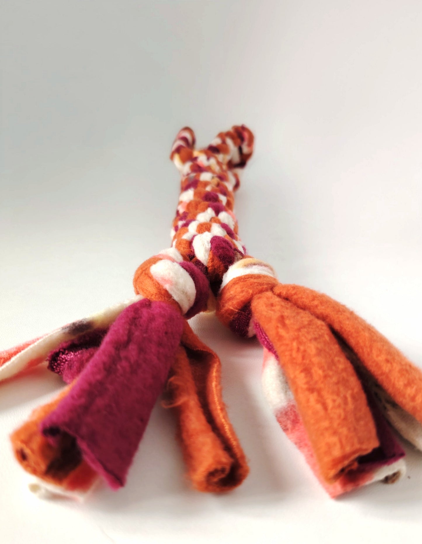 Close-up of the tasselled fleece end of the Autumn handled dog tug toy in warm seasonal colours.