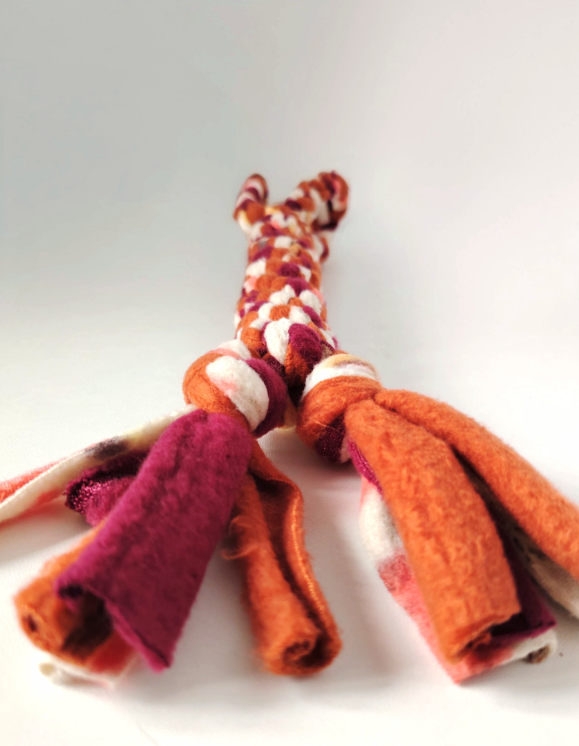 Close-up of the tasselled fleece end of the Autumn handled dog tug toy in warm seasonal colours.