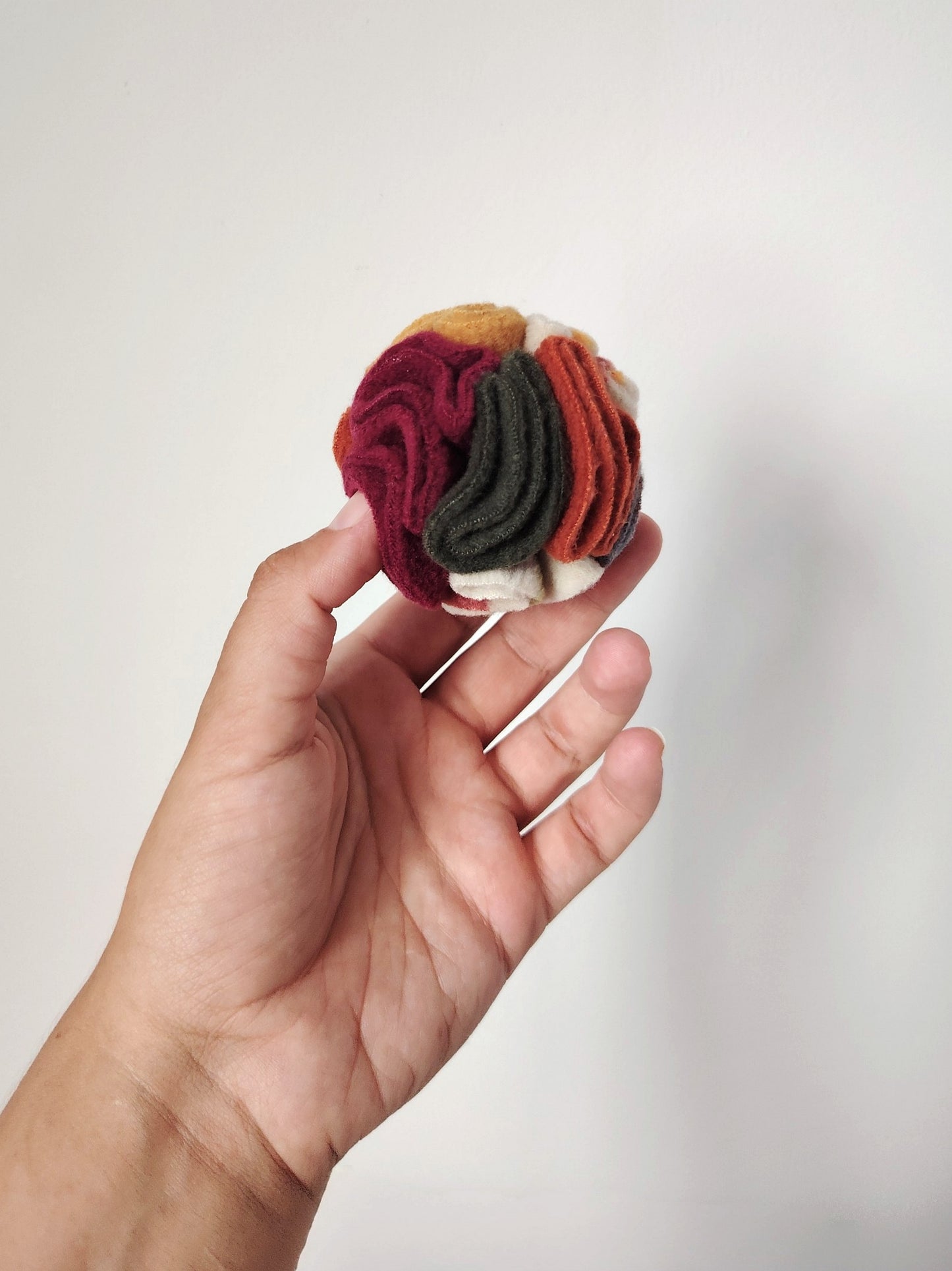 Autumn Pocket Snuffle Ball held in one hand to show its compact size.