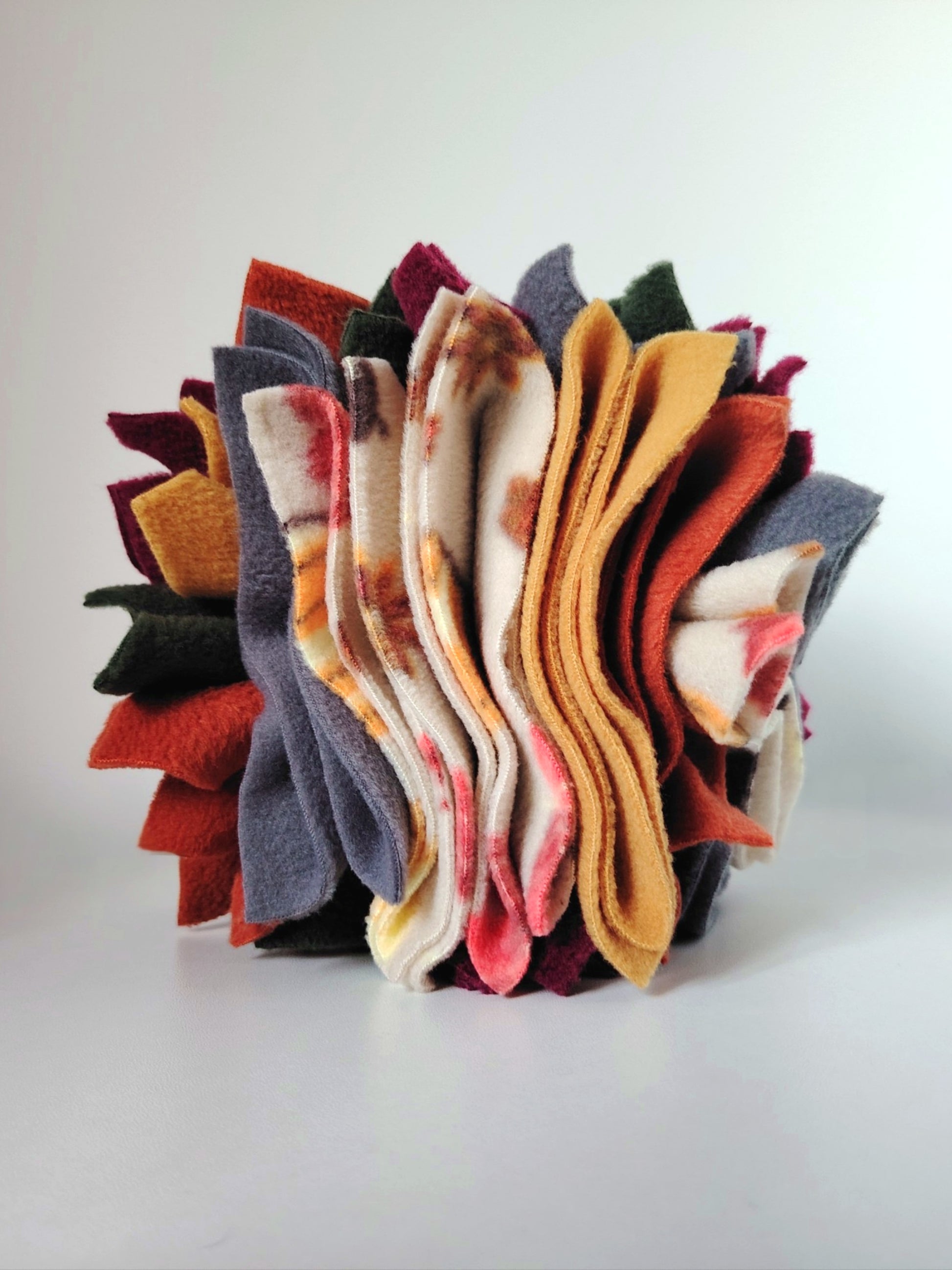 Nova Zeal Autumn Scruffle Ball showing layered rust, mustard, plum, grey and pattered fleece.