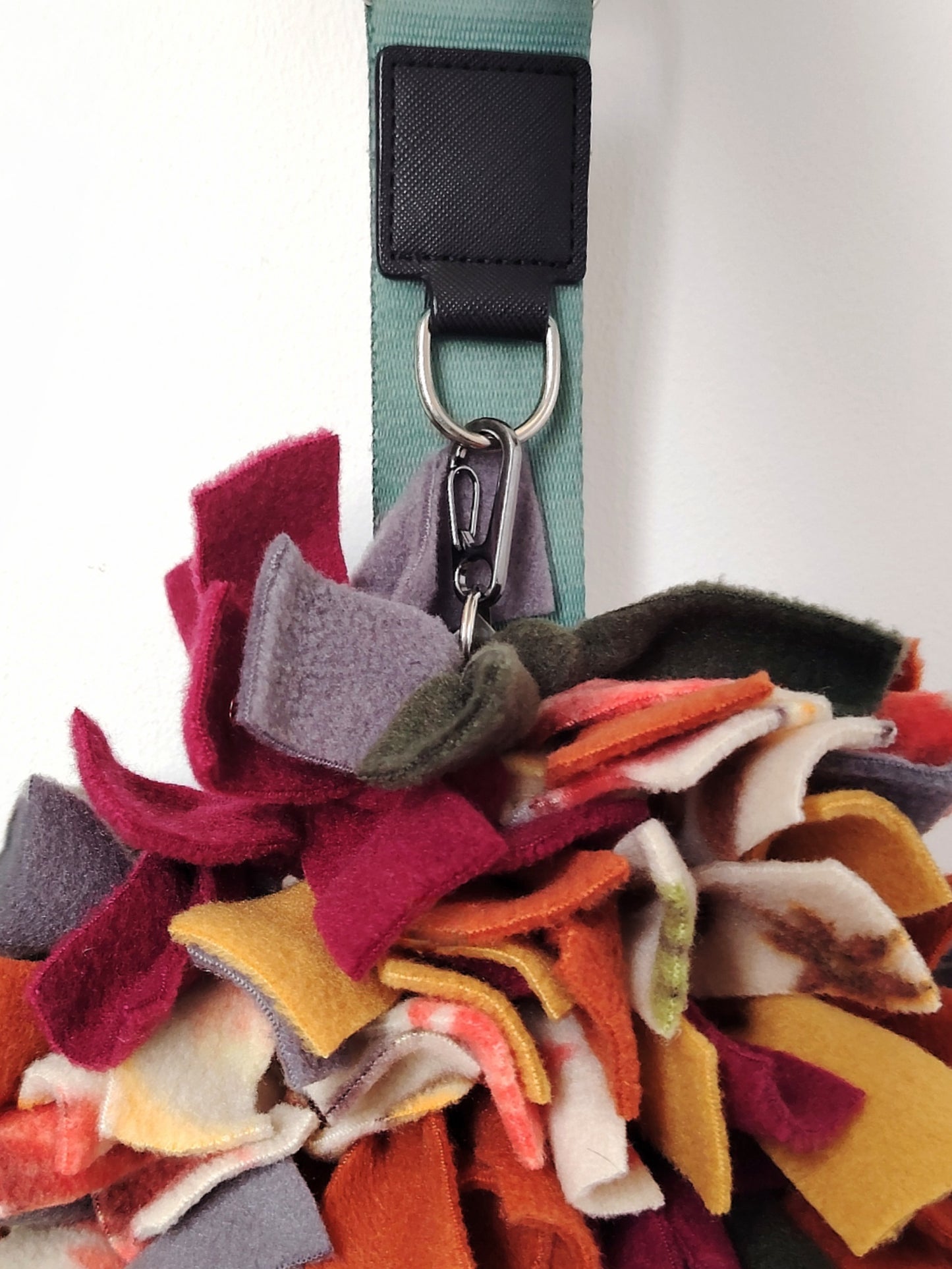 Autumn Snuffle Mat hanging from a bag using the attached carabiner for easy travel.