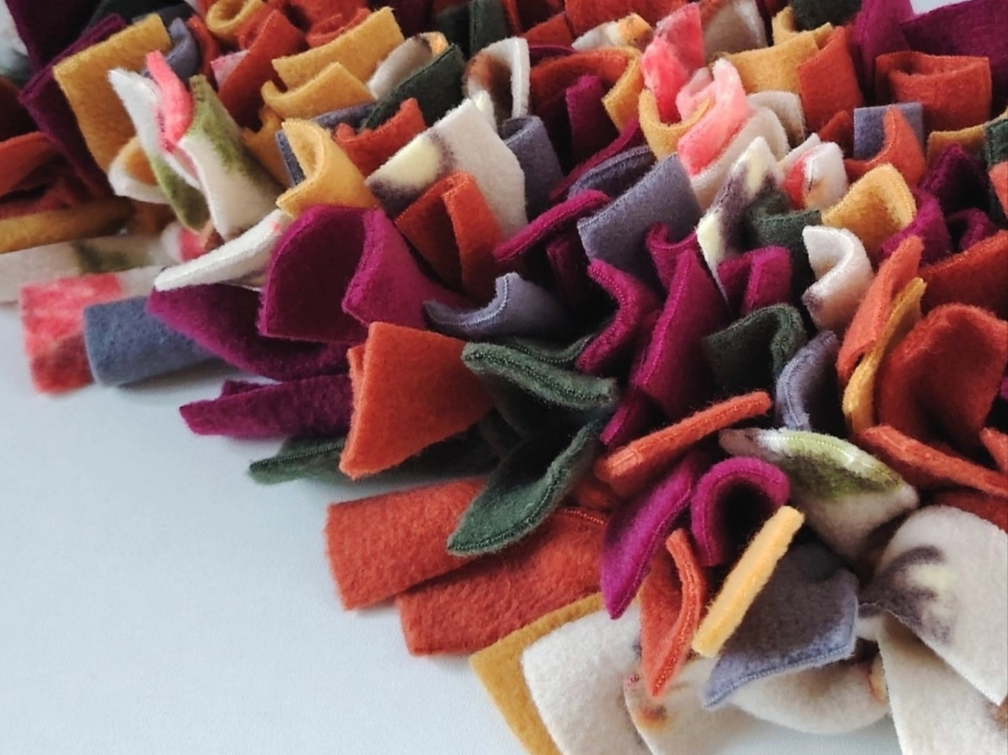 Close-up of Autumn Snuffle Mat with rust, mustard, plum, green, grey and patterned fleece strips.