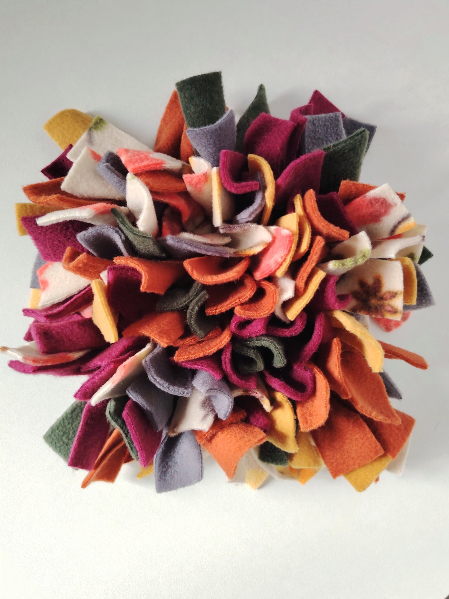 Handmade Autumn Snuffle Mat in rust, mustard, plum, forest green, and light charcoal fleece.
